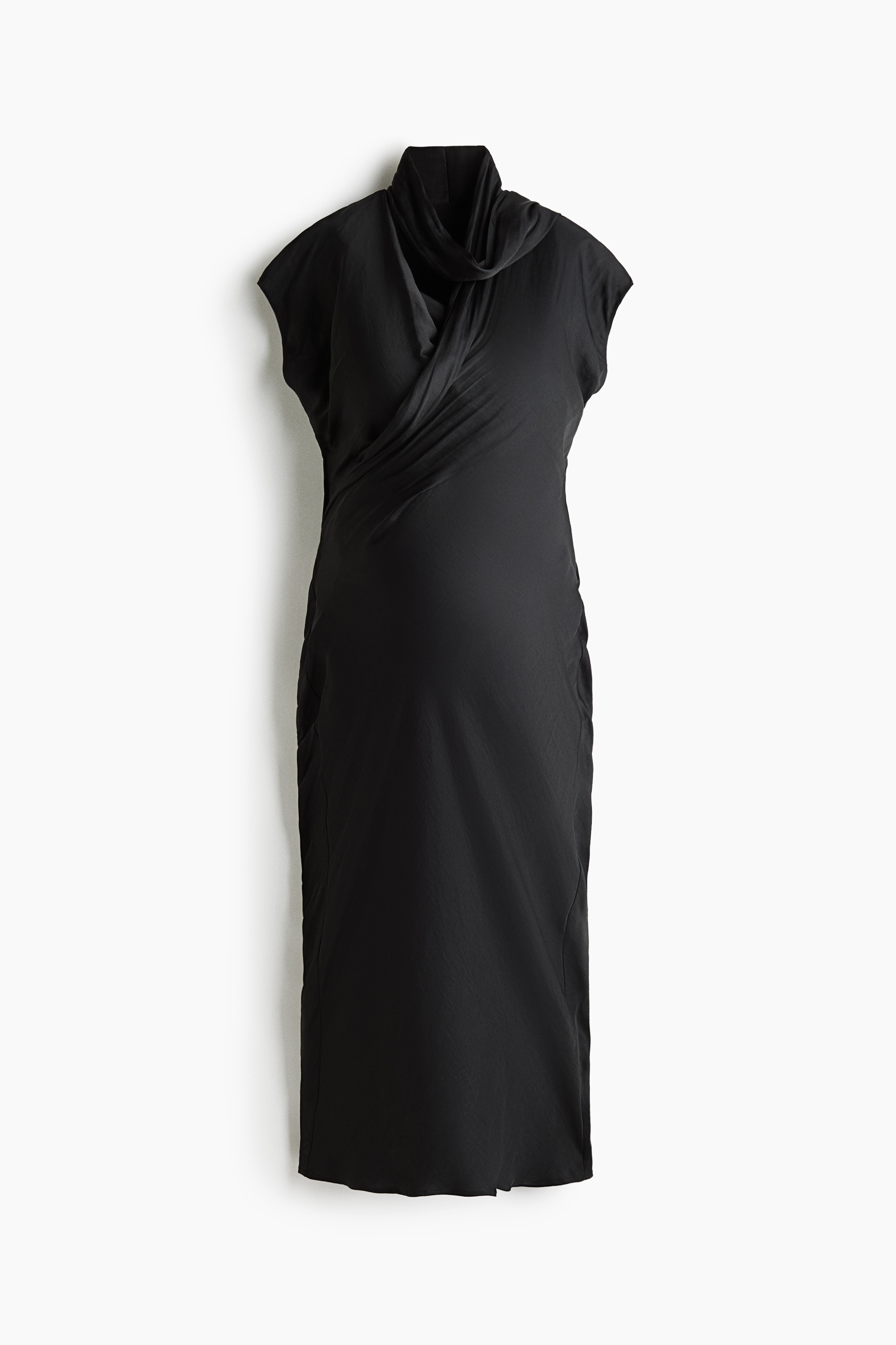 A calf-length, dark satin nursing dress is being worn by the model, featuring a wrap-front design, cap sleeves, and a V-shaped neckline. An attached long scarf detail is wrapped around the neck, which the model is lightly touching while standing in black heeled slide sandals.