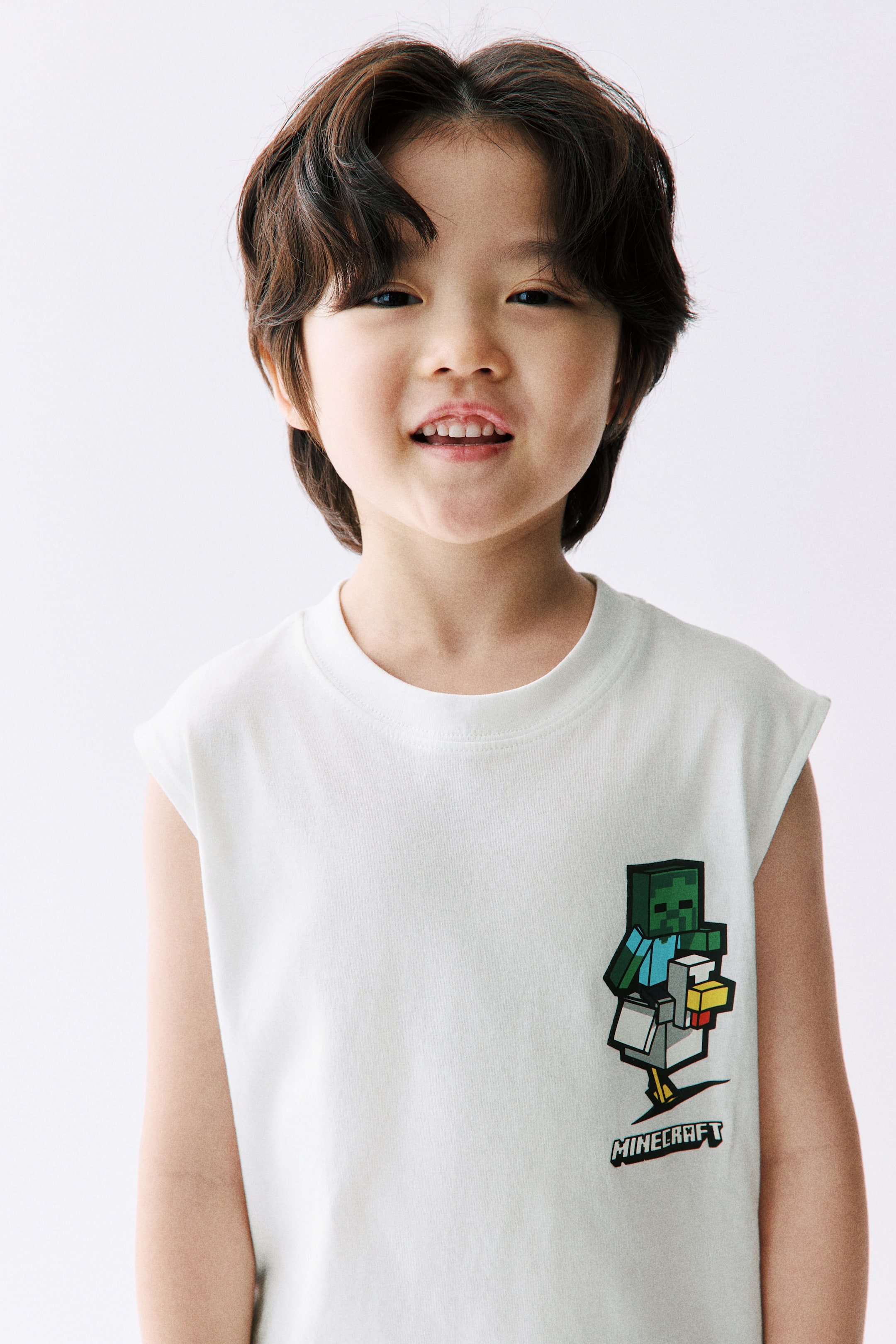 View larger image: A white sleeveless t-shirt menampilkan leher bulat dan cetakan grafik di bahagian hadapannya. Cetakan tersebut menggambarkan zombi Minecraft berpixel menunggang ayam berpixel, dengan perkataan 'MINECRAFT' dicetak di bawahnya.