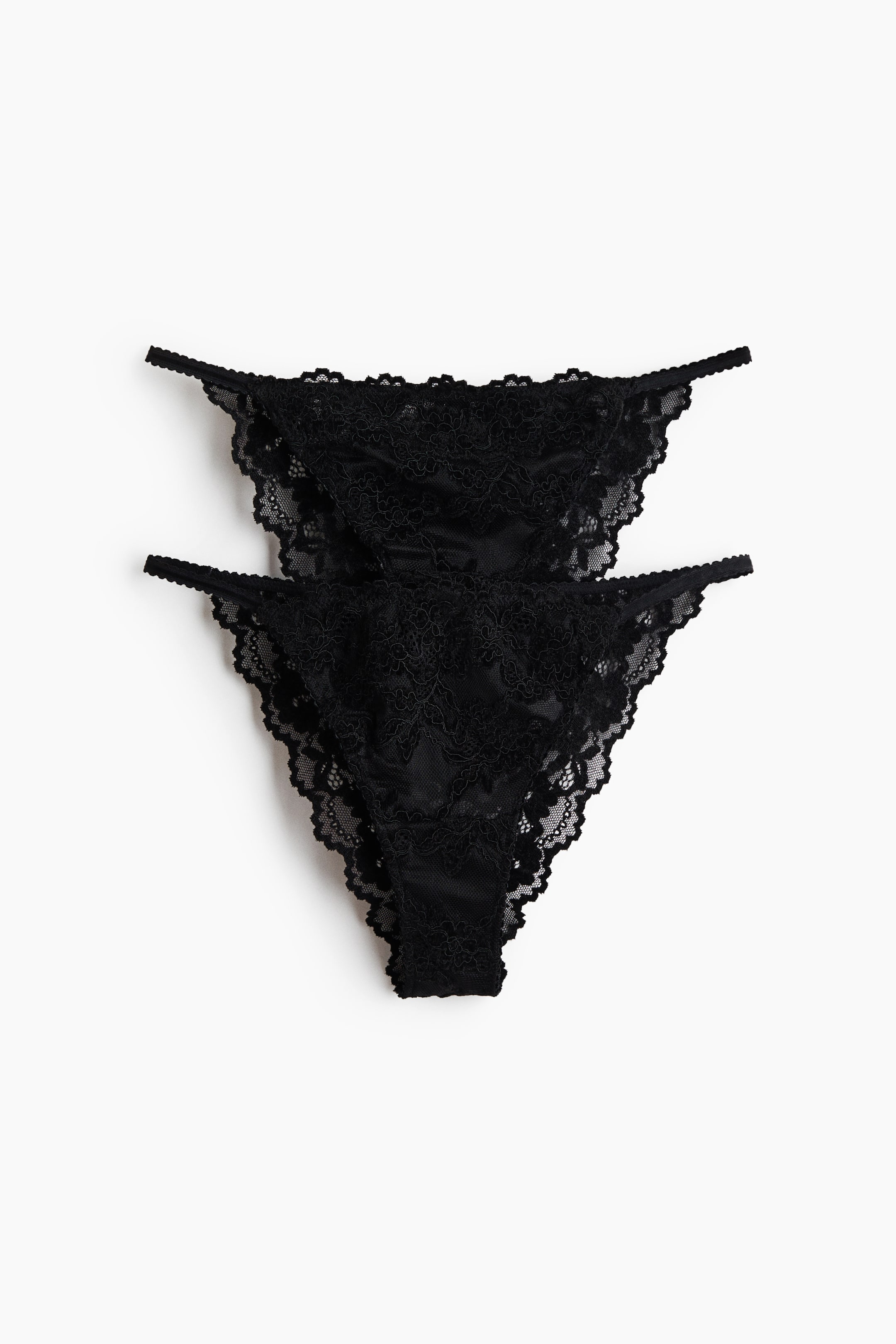 Visualizza immagine più grande: Sono mostrati due paia di slip in pizzo nero, ripresi frontalmente e impilati verticalmente. Entrambi i paia presentano inserti in pizzo trasparente a motivo floreale con bordi smerlati e sottili cinturini laterali elasticizzati.