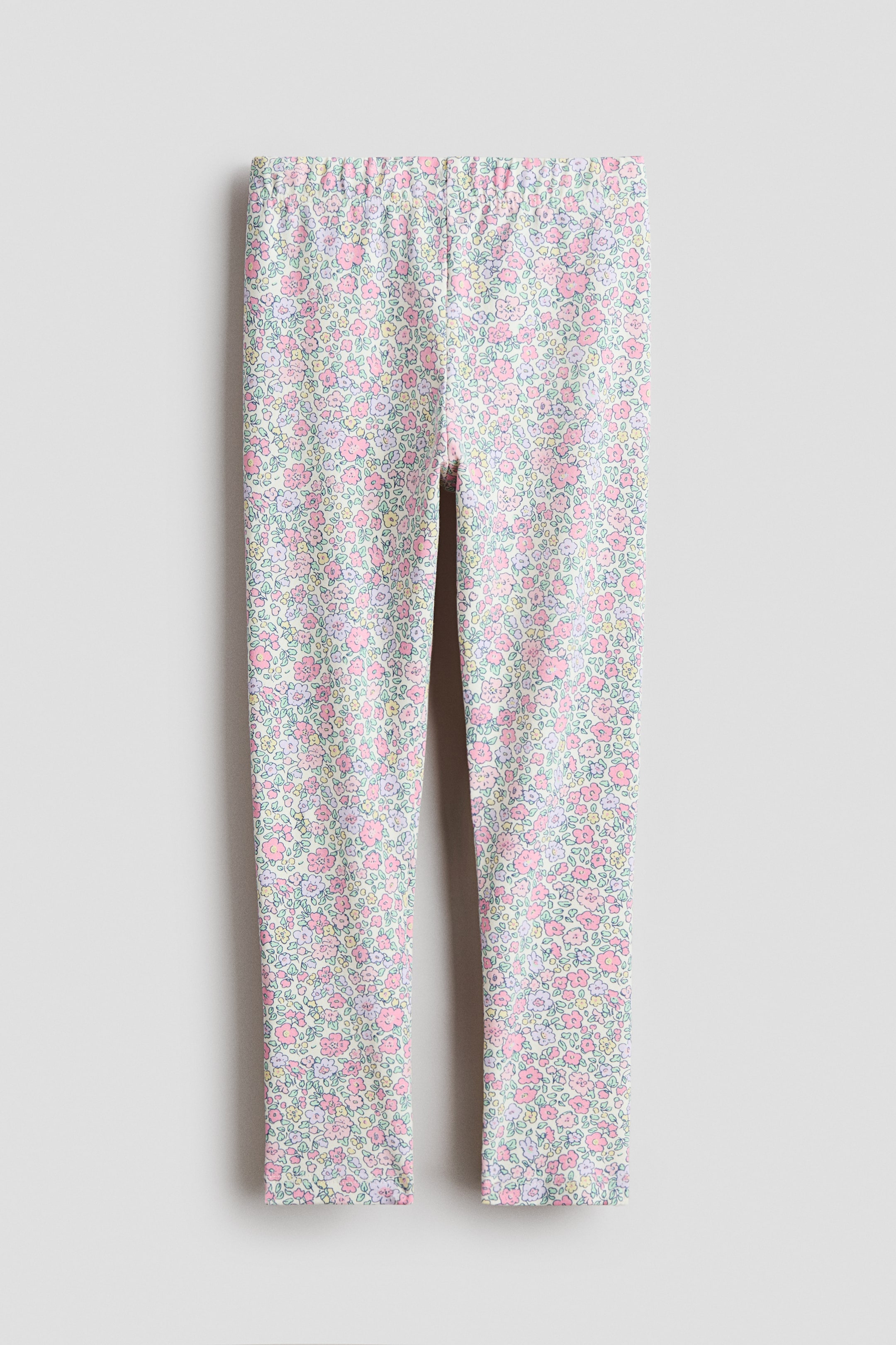 View larger image: The leggings are showcased from the front, crafted from a soft, printed cotton jersey fabric. They exhibit a rich floral design with petite light pink, yellow, green, and blue flowers set against a light backdrop, and feature covered elastication at the waist.