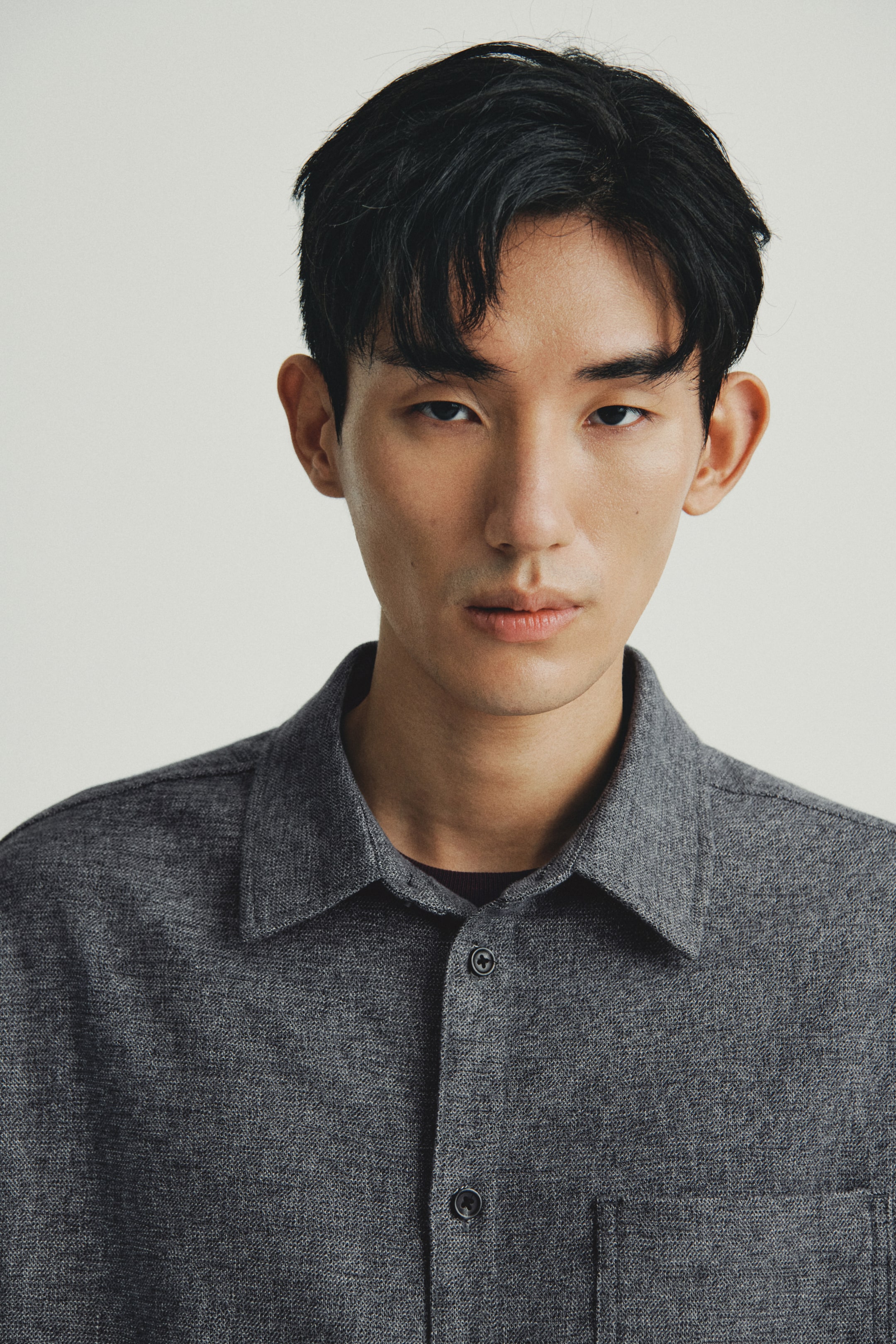 이미지 확대 보기: 어두운 회색 헤더 셔츠가 소개되고 있으며, 정면을 향하고 있습니다. 이 셔츠는 스프레드 칼라, 두 개의 어두운 버튼이 있는 앞 버튼 플래킷, 그리고 왼쪽 가슴에 패치 포켓이 특징입니다. 어두운 크루넥 셔츠가 아래에 레이어링되어 있습니다.