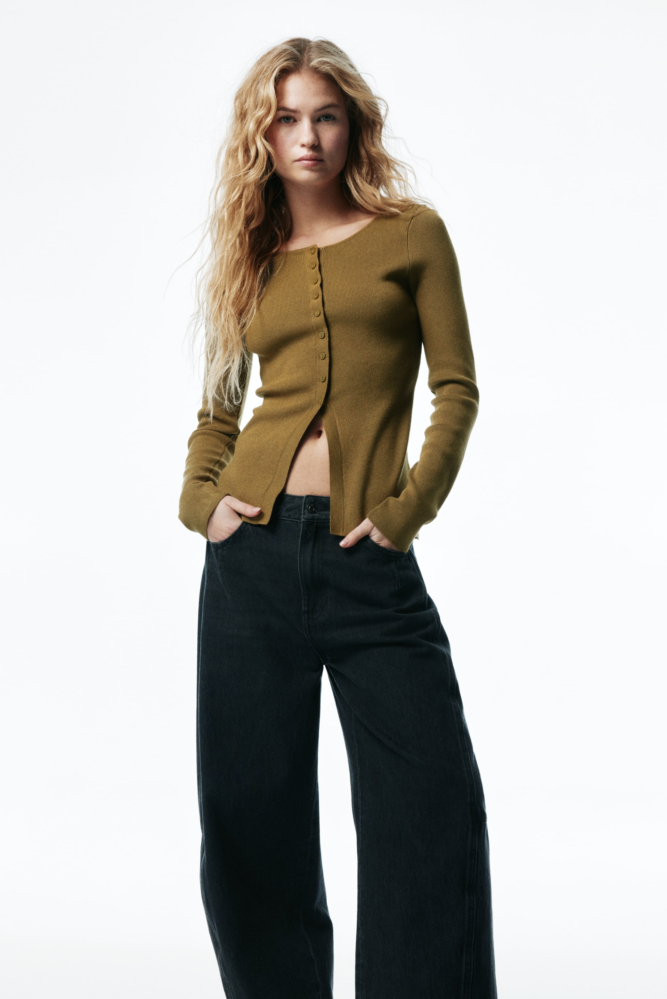 Prikaži veću sliku: Maslinasto zelena rebrasta majica dugih rukava prikazana je s prednje strane, sa okruglim izrezom i redom dugmića od kojih je nekoliko zakopčano. Majica se priljubljuje uz telo, stvarajući razdelen otvor na prednjem rubu.