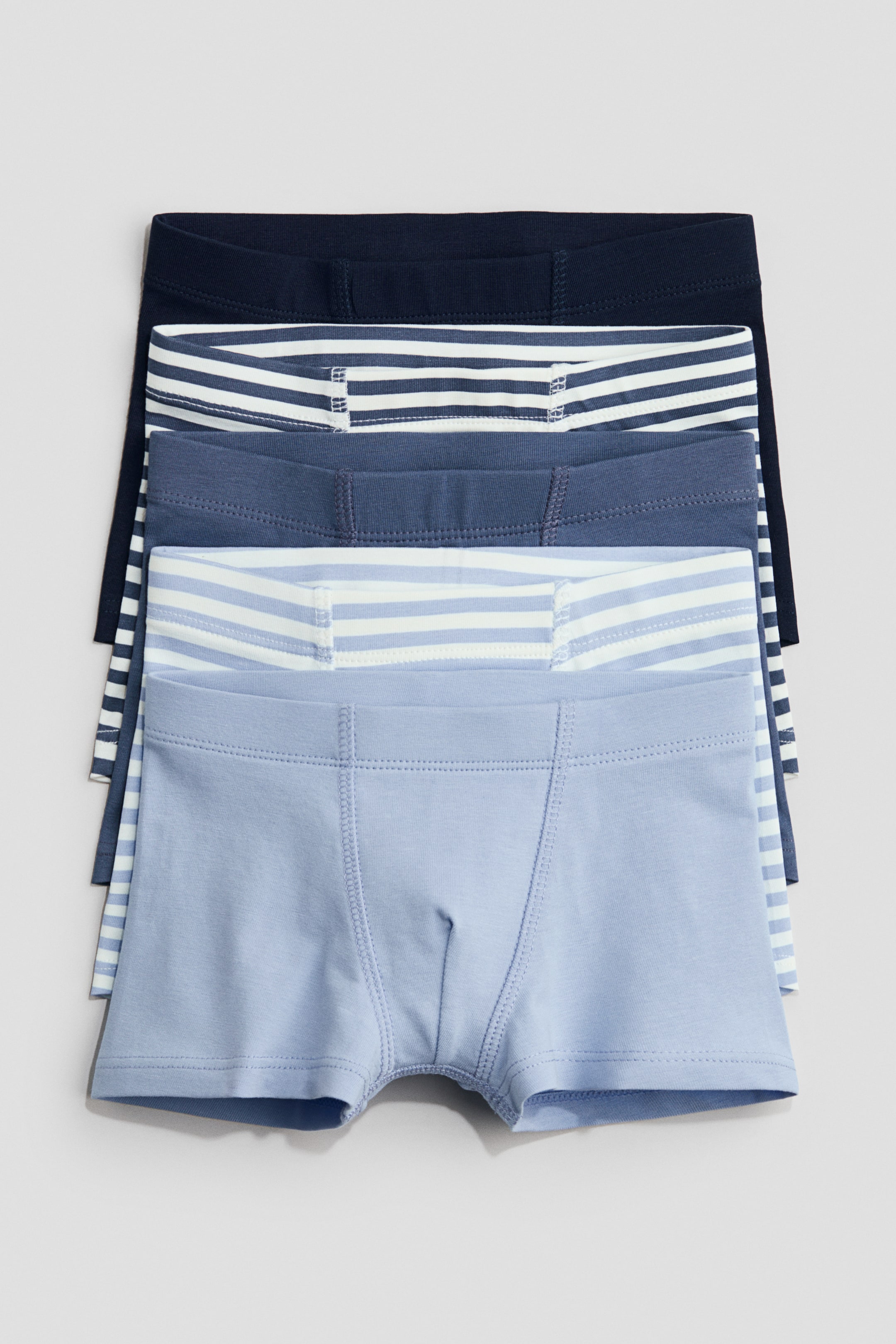 Grösseres Bild ansehen: Fünf Paar Boxershorts aus Baumwolljersey sind gestapelt und zeigen ihre VORDERSEITE. Jedes Paar verfügt über kurze Beine, einen elastischen Bund und ein gefüttertes Vorderteil. Die Farben reichen von einfarbigem Marineblau und marineblau-weißen Streifen bis hin zu einfarbigem Mittelblau, hellblau-weißen Streifen und einfarbigem Hellblau.