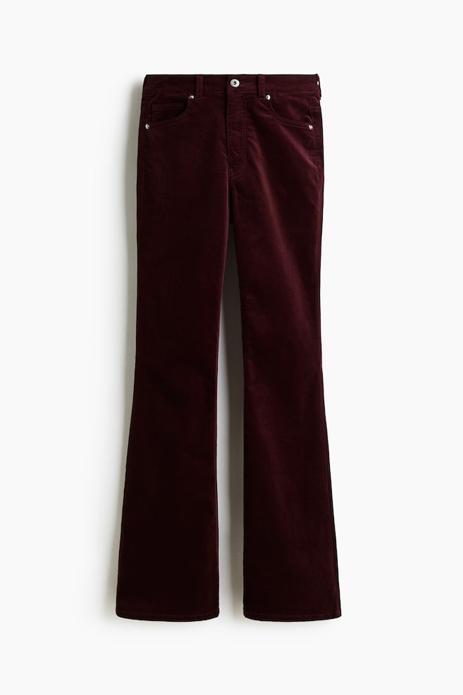 Maroon corduroy pants are presenting a front view, featuring a button closure at the waist, scoop front pockets with metal rivets, and a flared leg style widening from the knee down. - 1