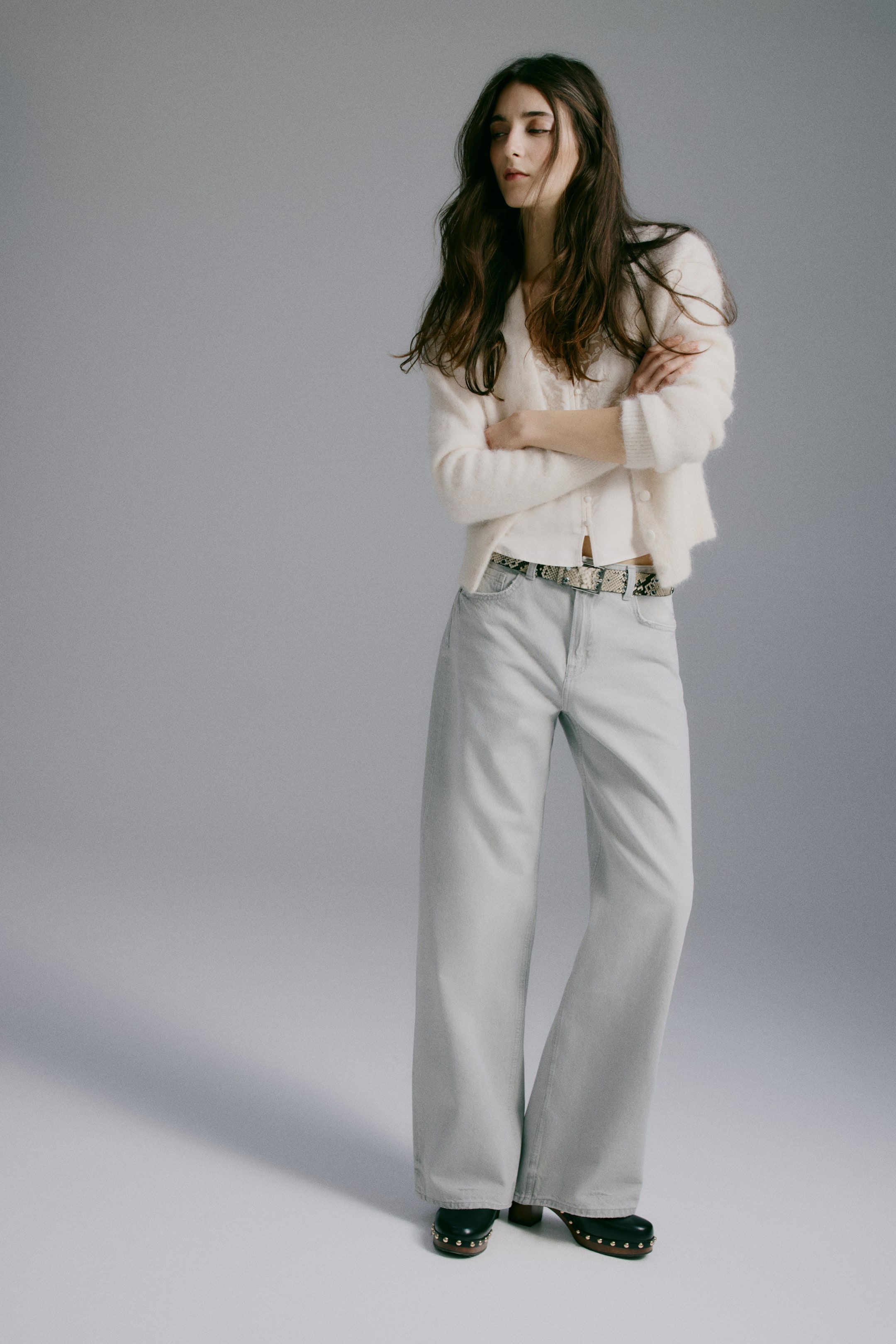 Xem ảnh lớn hơn: Quần jeans denim 5 túi bằng vải cotton đã giặt, có cạp cao, khóa kéo và cúc, ống quần rộng và thẳng đang được người mẫu mặc. Người mẫu cũng đang đeo một chiếc thắt lưng có họa tiết xỏ qua các vòng đai của quần jeans.