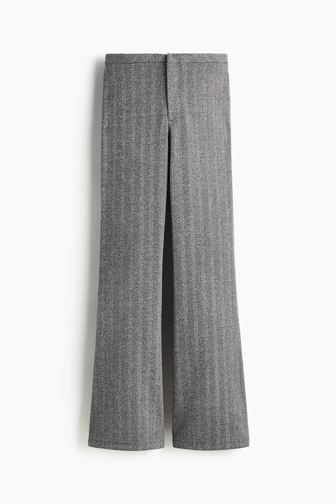 Eine Hose mit weitem Bein hängt und zeigt ein grau-weißes Fischgrätenmuster. Sie verfügt über einen flachen Bund und einen verdeckten Frontverschluss. - 1