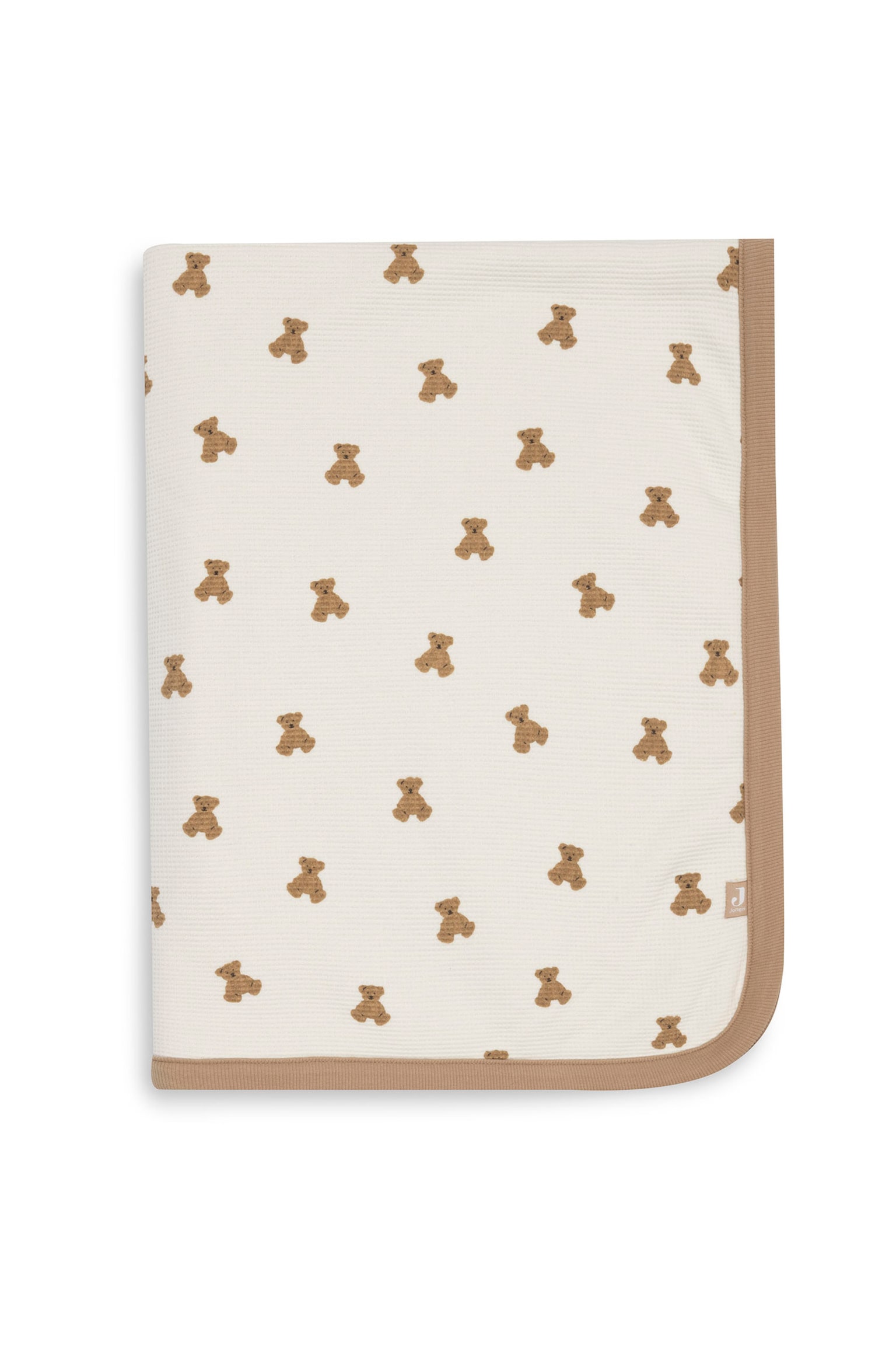 Een babydeken ligt plat in een opgevouwen presentatie, met een all-over patroon van kleine bruine teddyberen op een gebroken witte wafelkatoenen stof. Een effen tan geribde bies omlijst de onder- en rechterrand van de deken.