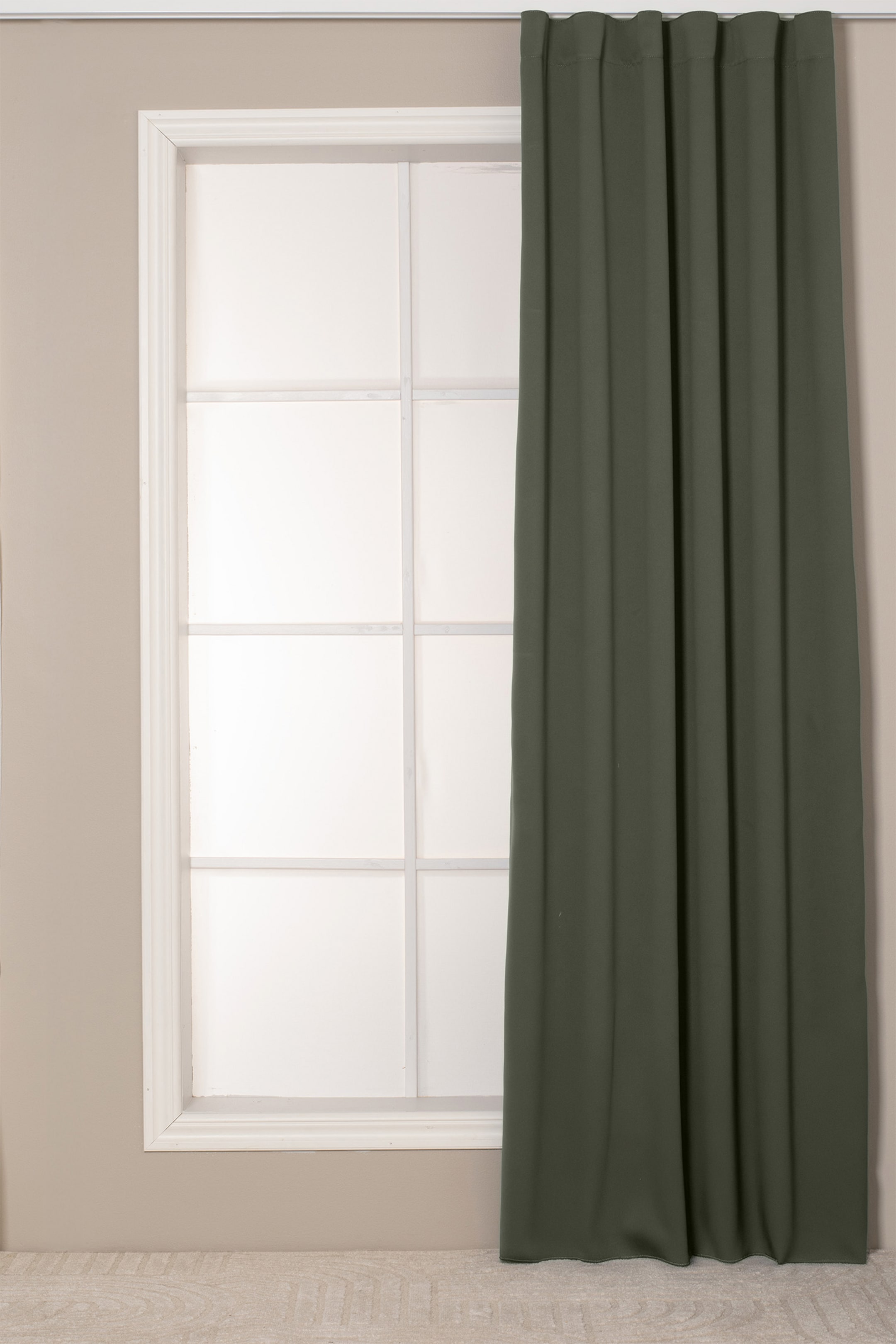 Se større billede: Et mørkegrønt gardinpanel hænger lige og fremviser sit glatte, matte stof. Det har en struktureret plisseret top, der danner bløde, lodrette folder langs hele længden.
