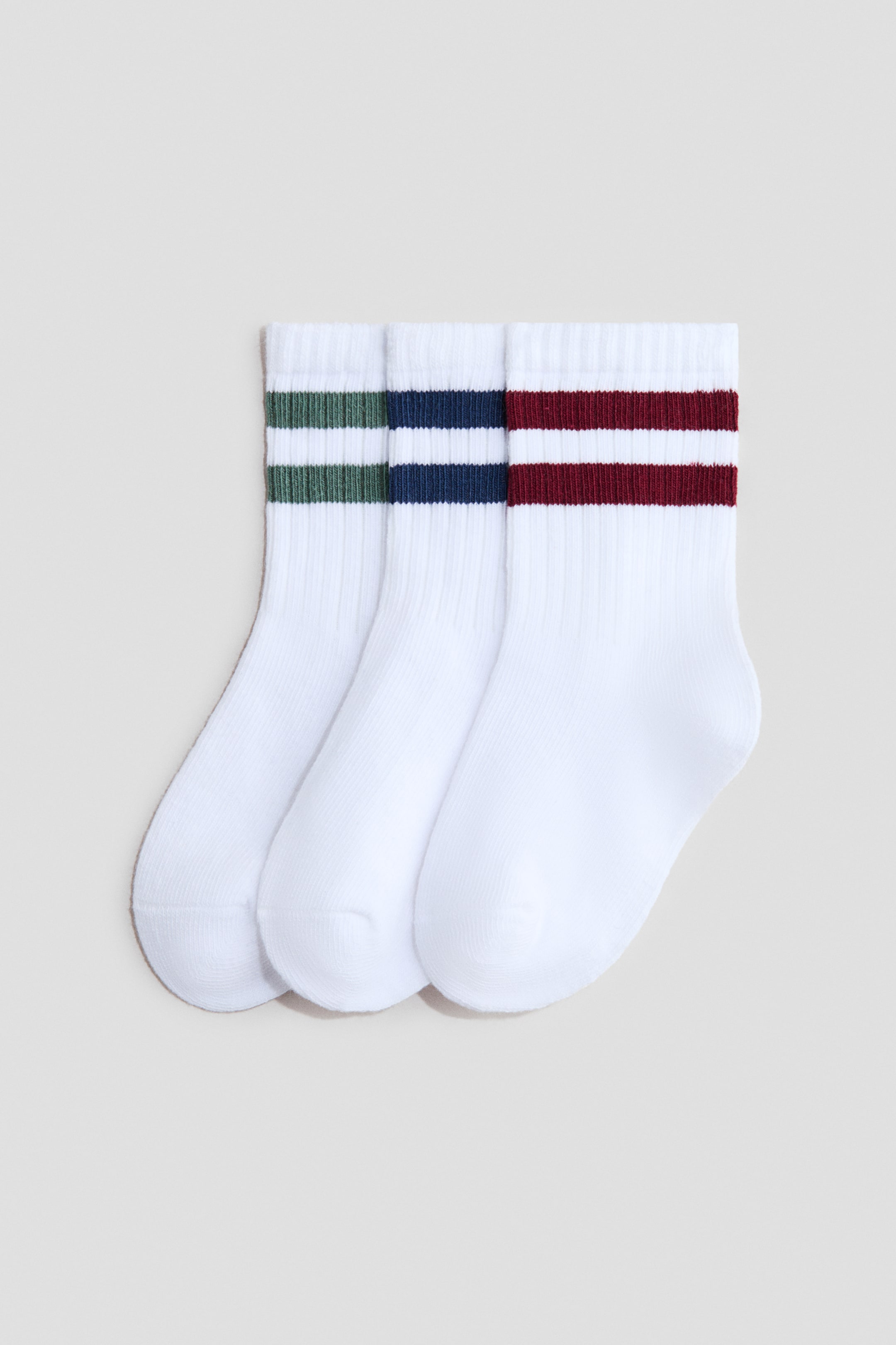 View larger image: Three fine-knit white socks feature ribbed cuffs and two horizontal stripes. The stripes appear in green, navy blue, and burgundy.