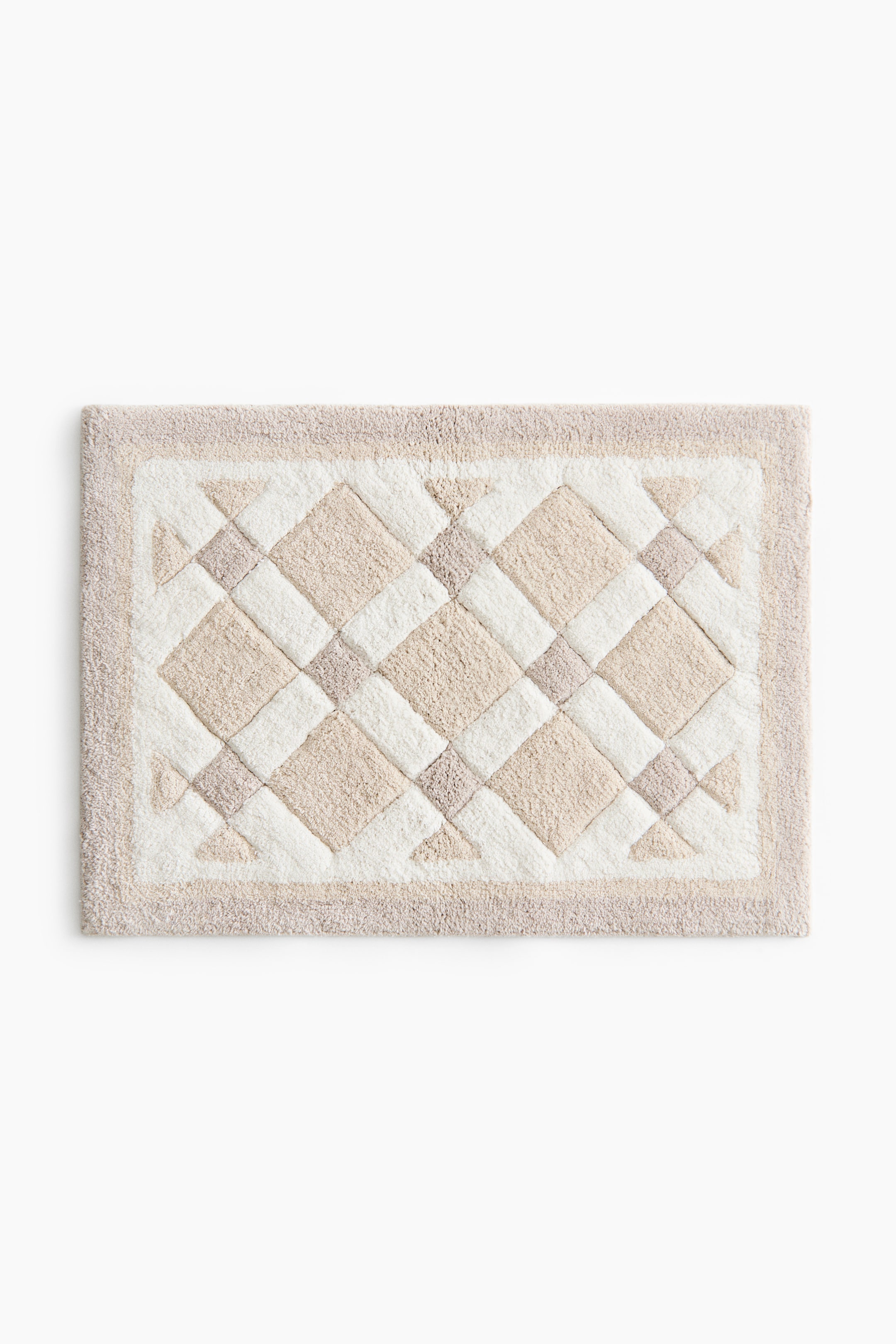 View larger image: A rectangular bath mat featuring a tufted surface with a geometric diamond and triangle pattern. The design showcases alternating sections of cream, light beige, and darker beige, all framed by a cream inner border and a light beige outer border.