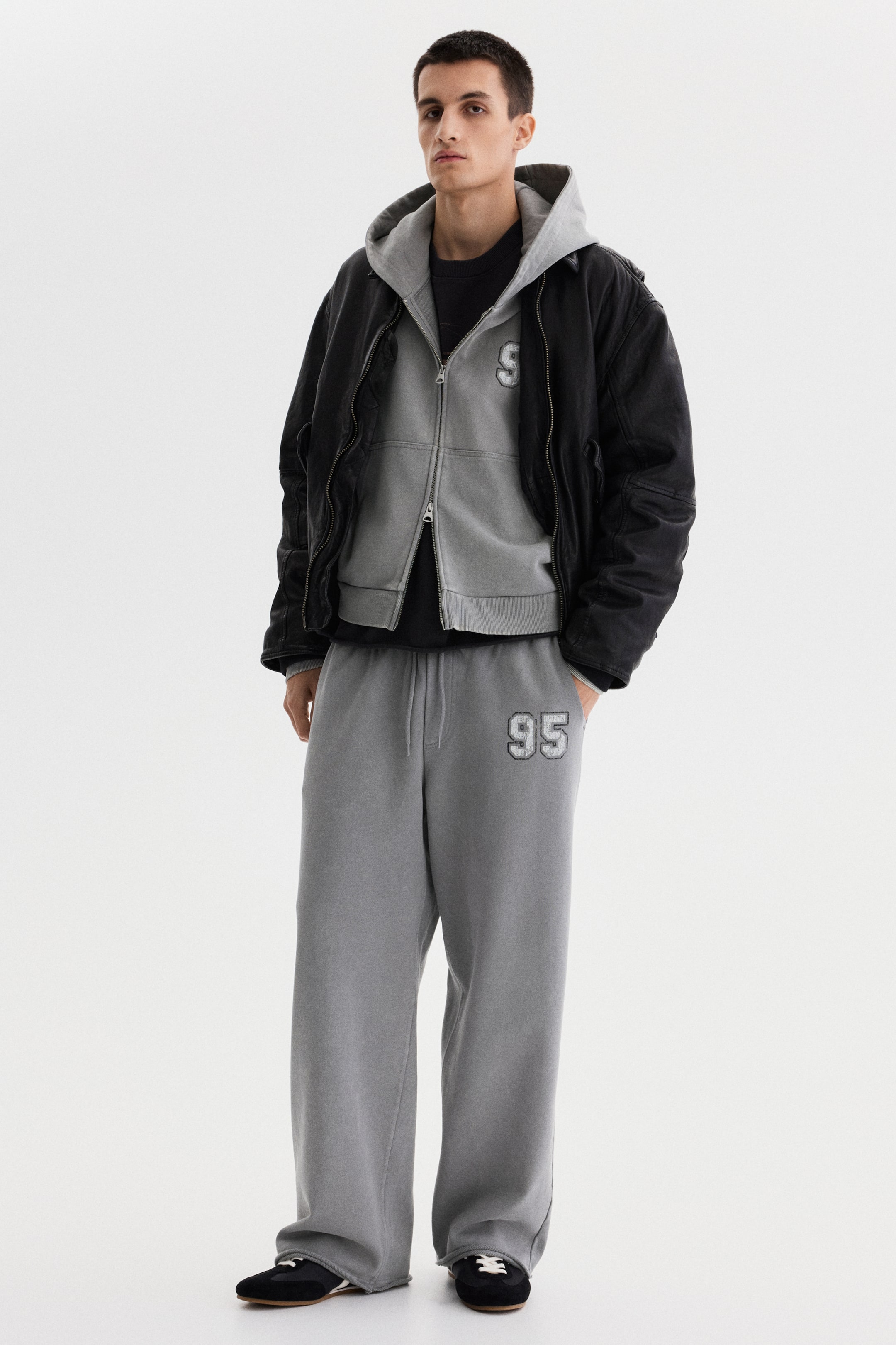 View larger image: Washed grey, wide-leg sweatpants feature a loose fit, a drawstring waist, and an uncuffed hem. A textured "95" graphic appears on the left thigh.