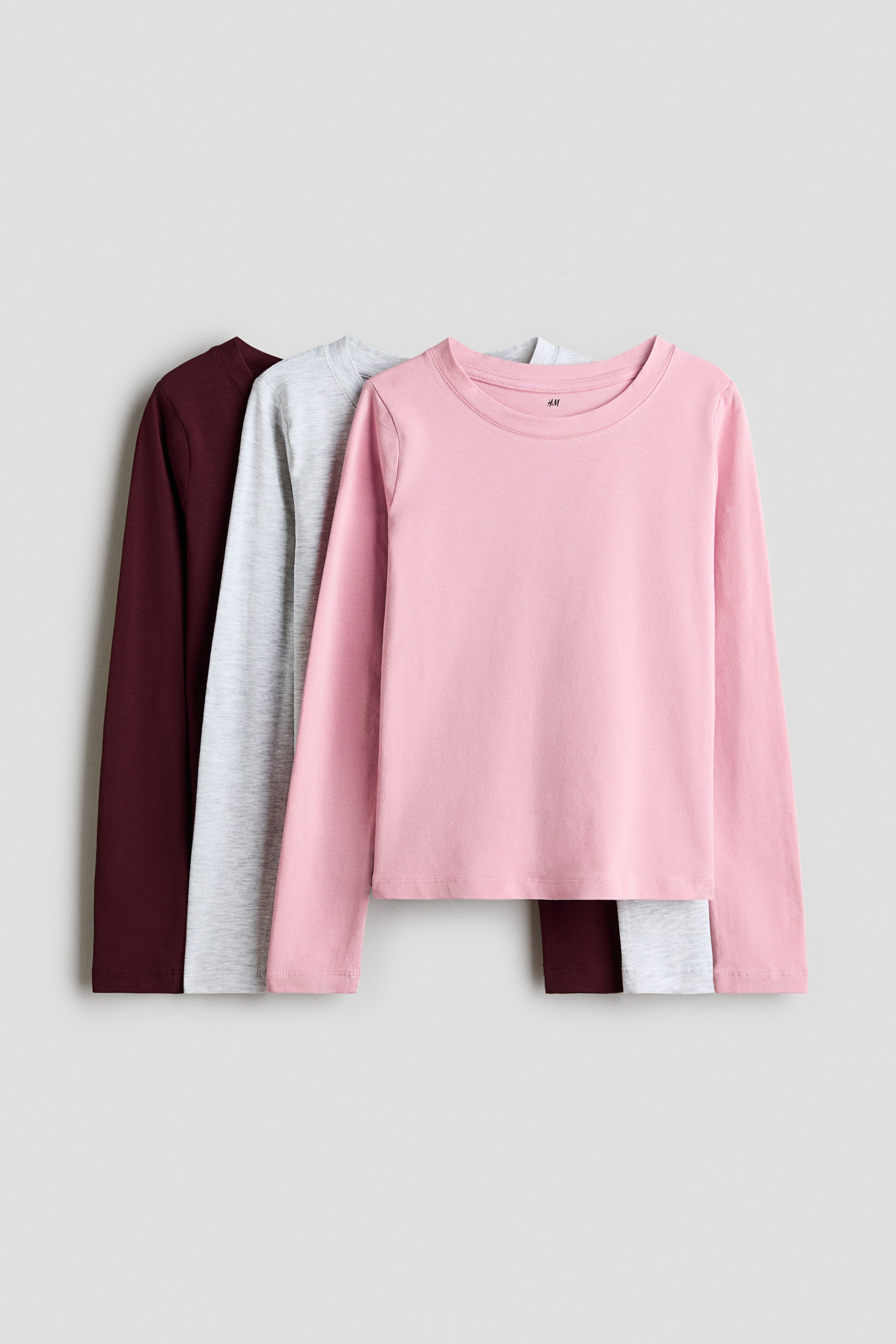 View larger image: Set of three long-sleeved T-shirts crafted from soft cotton jersey, showcasing a round neckline with a narrow trim. The collection is displayed front-facing, featuring shirts in burgundy, light grey marl, and light pink, with the pink shirt elegantly layered on top.