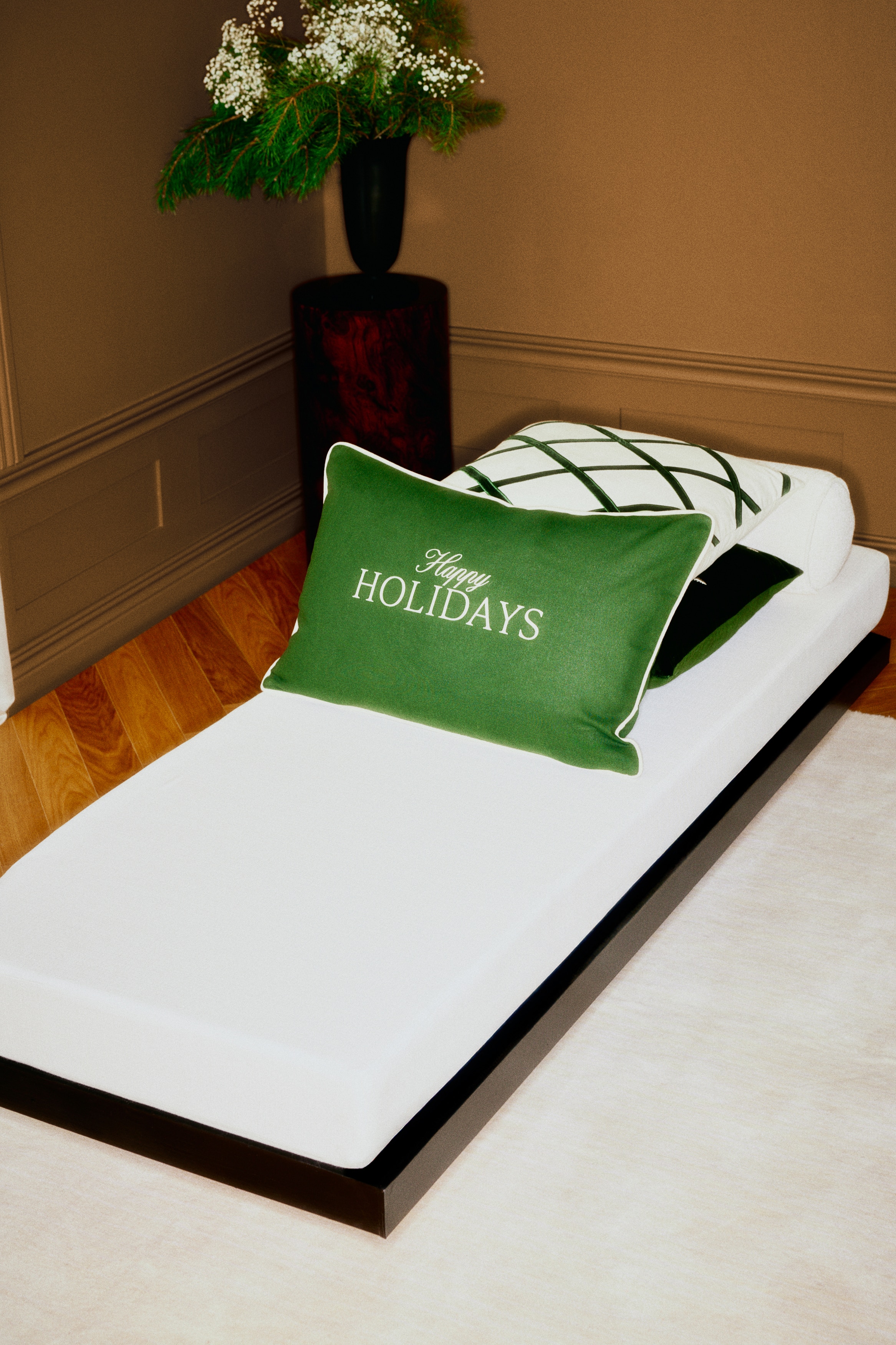 Un coussin rectangulaire vert foncÃ©, vu de face, affiche au centre le texte brodÃ© de couleur crÃ¨me Â« Happy HOLIDAYS Â», avec Â« Happy Â» en Ã©criture cursive et Â« HOLIDAYS Â» en lettres capitales sÃ©rif. Le coussin prÃ©sente un fin passepoil de couleur crÃ¨me le long de ses bords extÃ©rieurs.