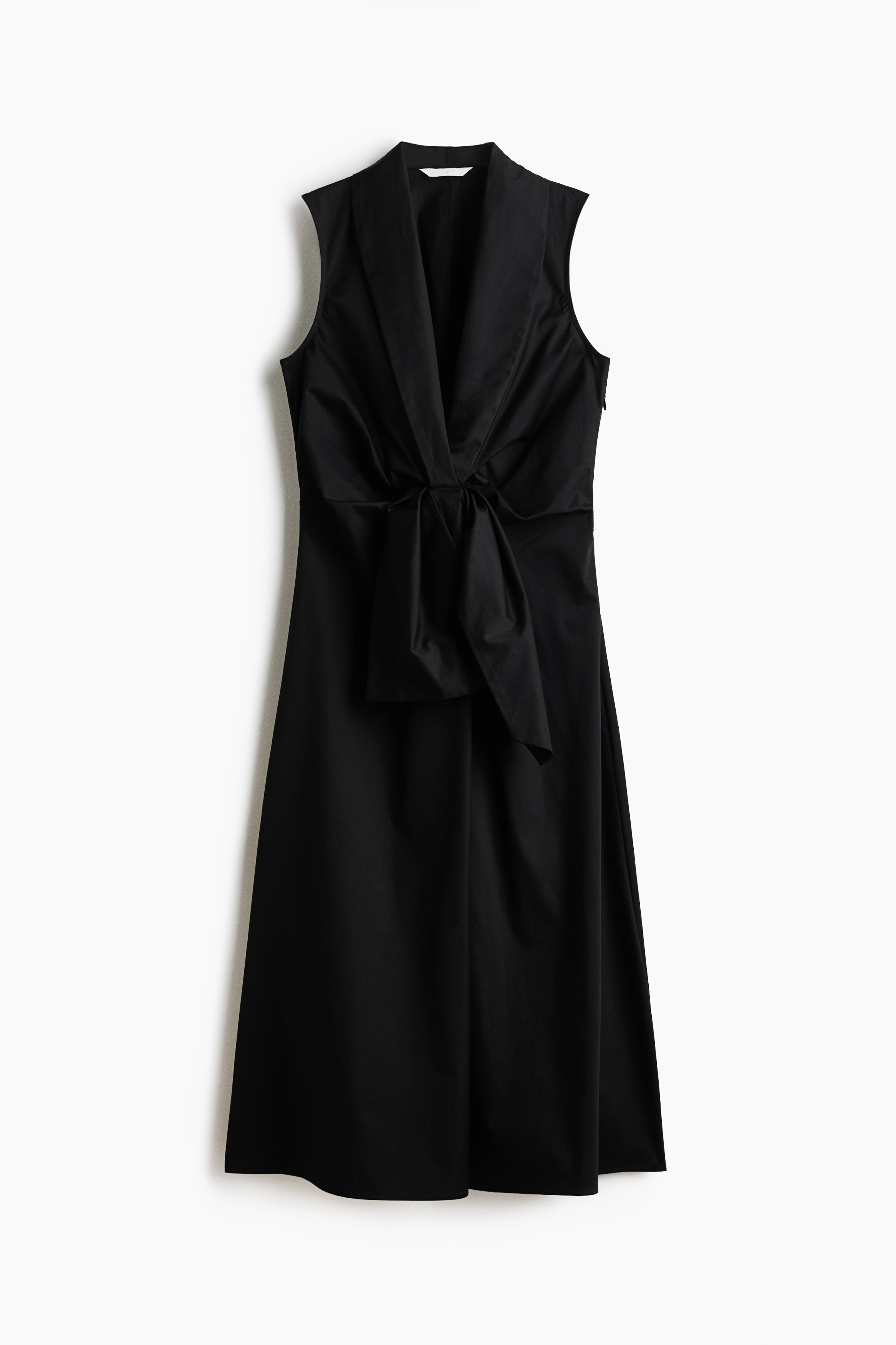 A black, calf-length, sleeveless dress is being worn by the model. The dress features a deep V-neck with wide lapels, a fitted bodice, and a prominent pleated tie detail at the waist that drapes over a gently flared skirt.