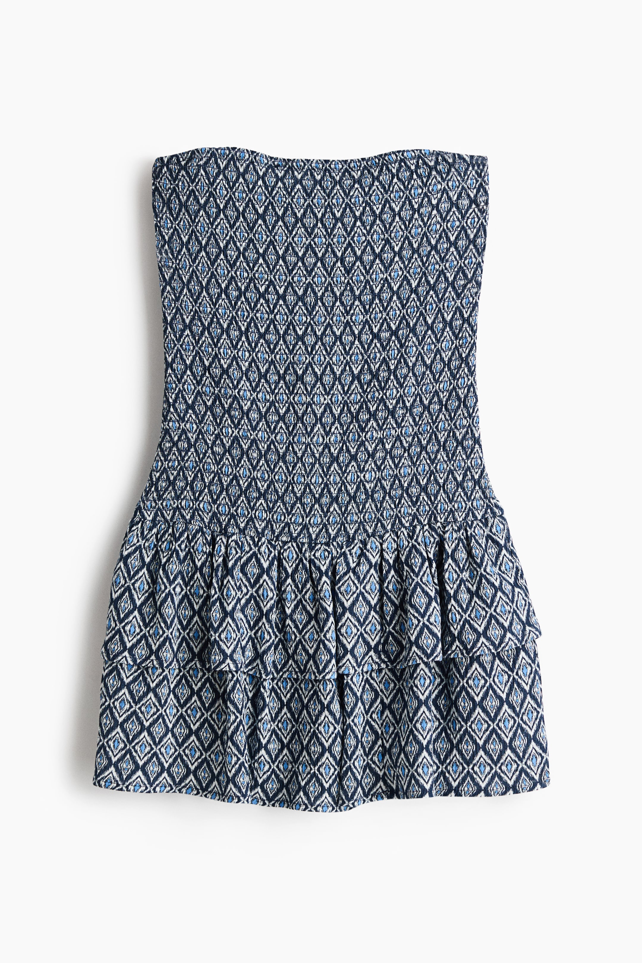 View larger image: This strapless dress showcases a dark blue, light blue, and white diamond pattern. The bodice is shirred, offering a snug texture, while the skirt is tiered and ruffled, elegantly flaring from the waist.