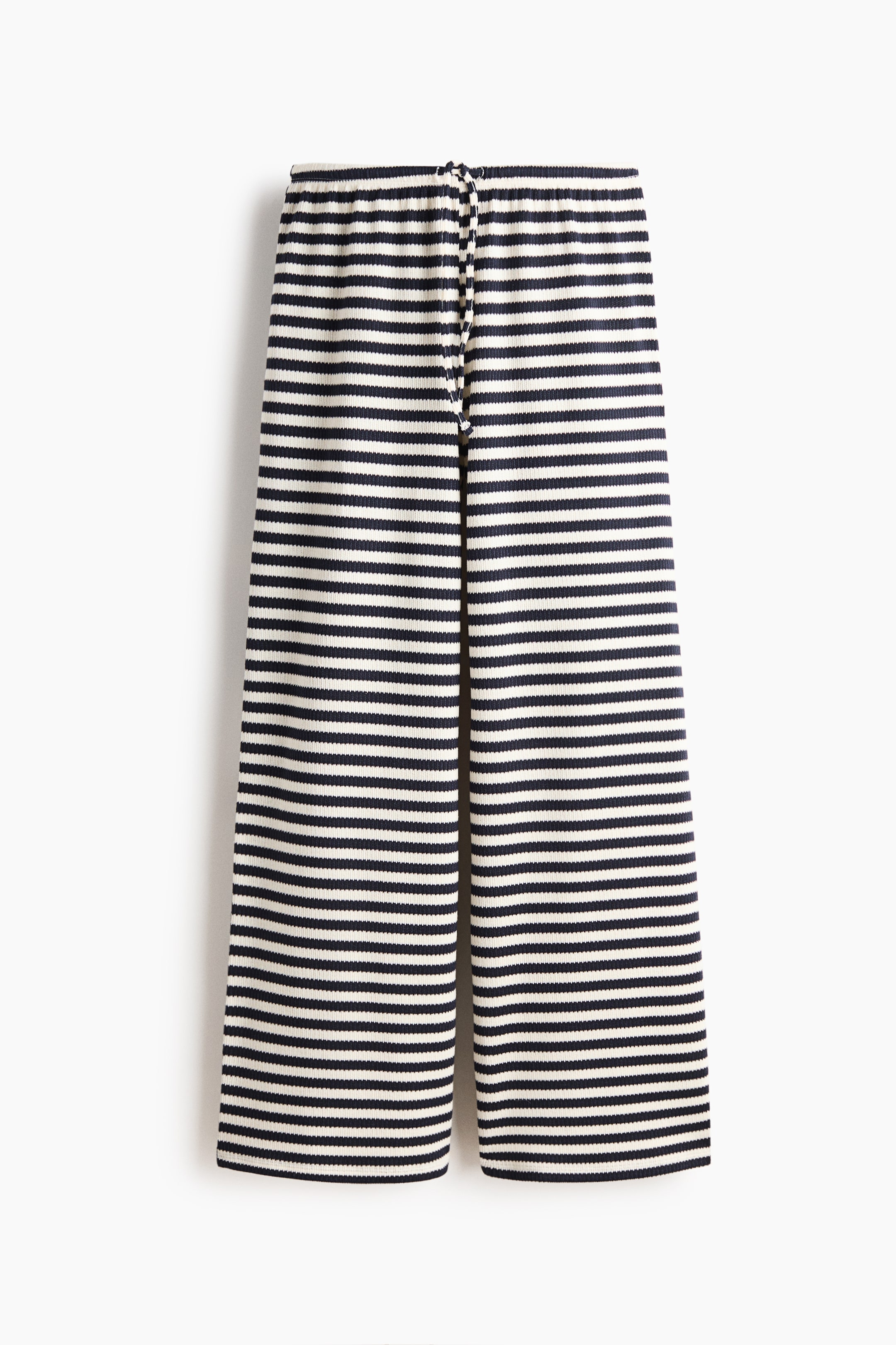 הצגת תמונה גדולה יותר: החלק הקדמי של המכנסיים מציג פסים אופקיים בצבע כחול כהה ולבן שבור בבד סרוג מצולע. הם כוללים חגורת מותן אלסטית עם שרוך קשירה גלוי ורגליים רחבות ומקוצרות.