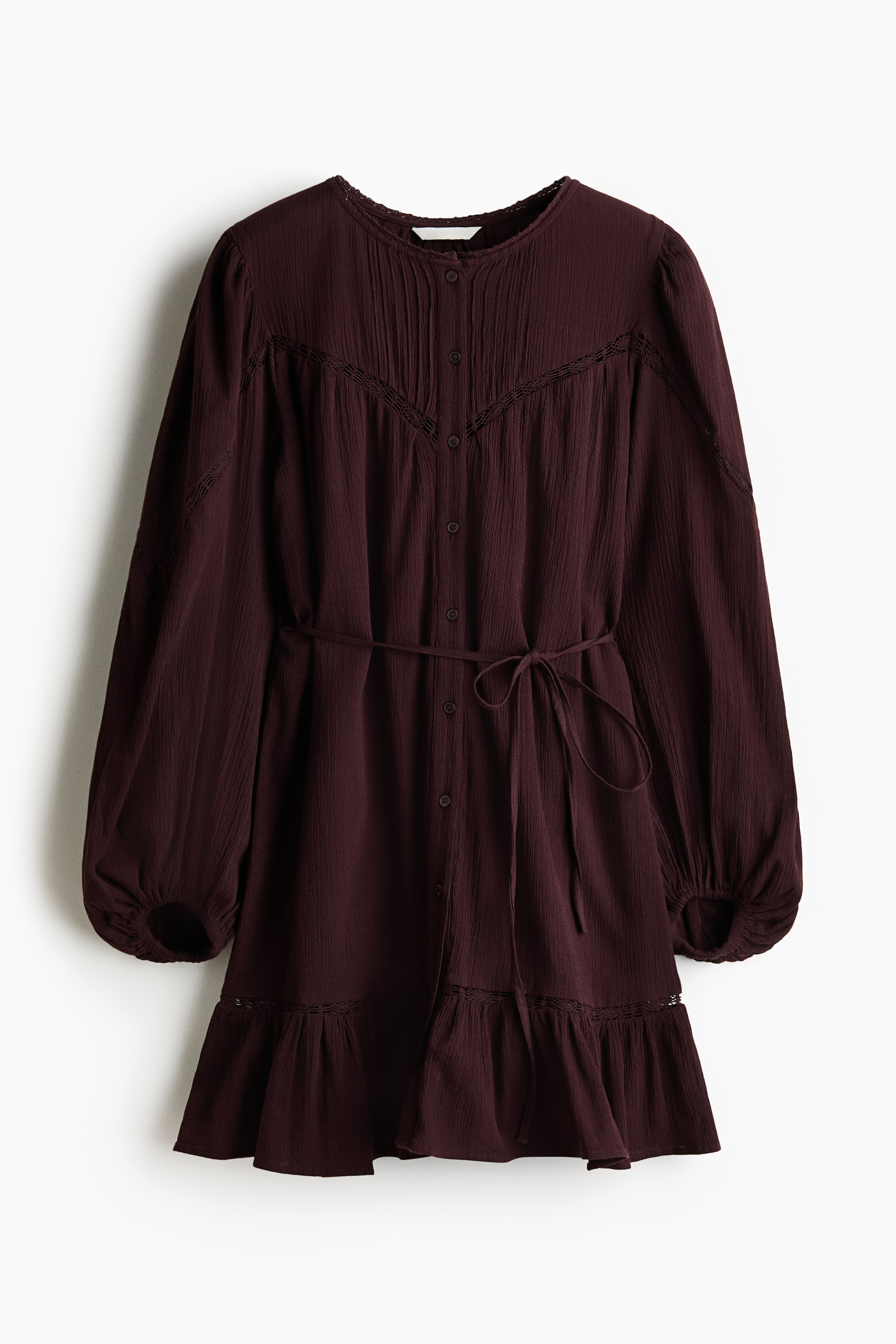 View larger image: A maroon, short, loose-fit tunic dress is showcasing its front, crafted from a crinkled cotton weave with lace insets throughout the design. It features a round neckline with a small lace trim, buttons running down the front, long balloon sleeves with elasticated cuffs, and a narrow tie belt cinching the waist, with a gathered seam above the hem adding volume.