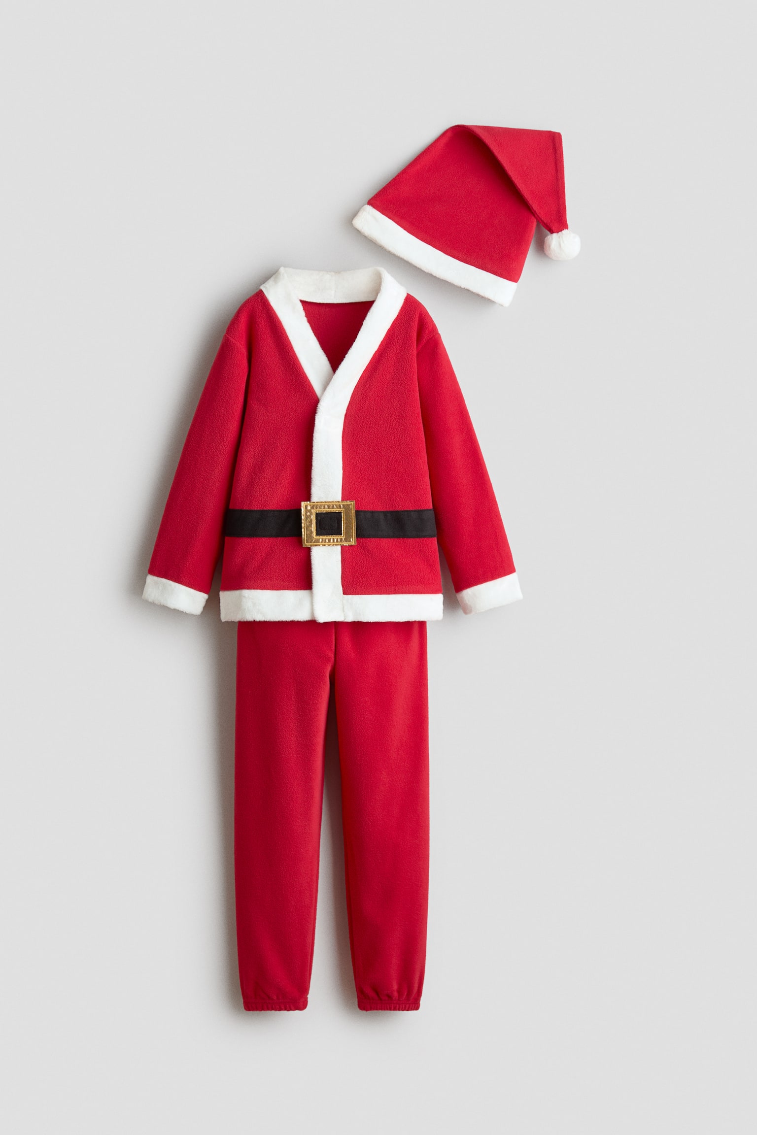 Un costume de PÃ¨re NoÃ«l en polaire rouge pour enfant est prÃ©sentÃ© de face, composÃ© dâun haut Ã  manches longues, dâun pantalon assorti et dâun chapeau pointu. Le haut prÃ©sente une bordure en fausse fourrure blanche au niveau du col, des poignets et de lâourlet, agrÃ©mentÃ©e dâun dÃ©tail de ceinture noire avec une boucle couleur or, tandis que le pantalon affiche des poignets Ã©lastiquÃ©s.