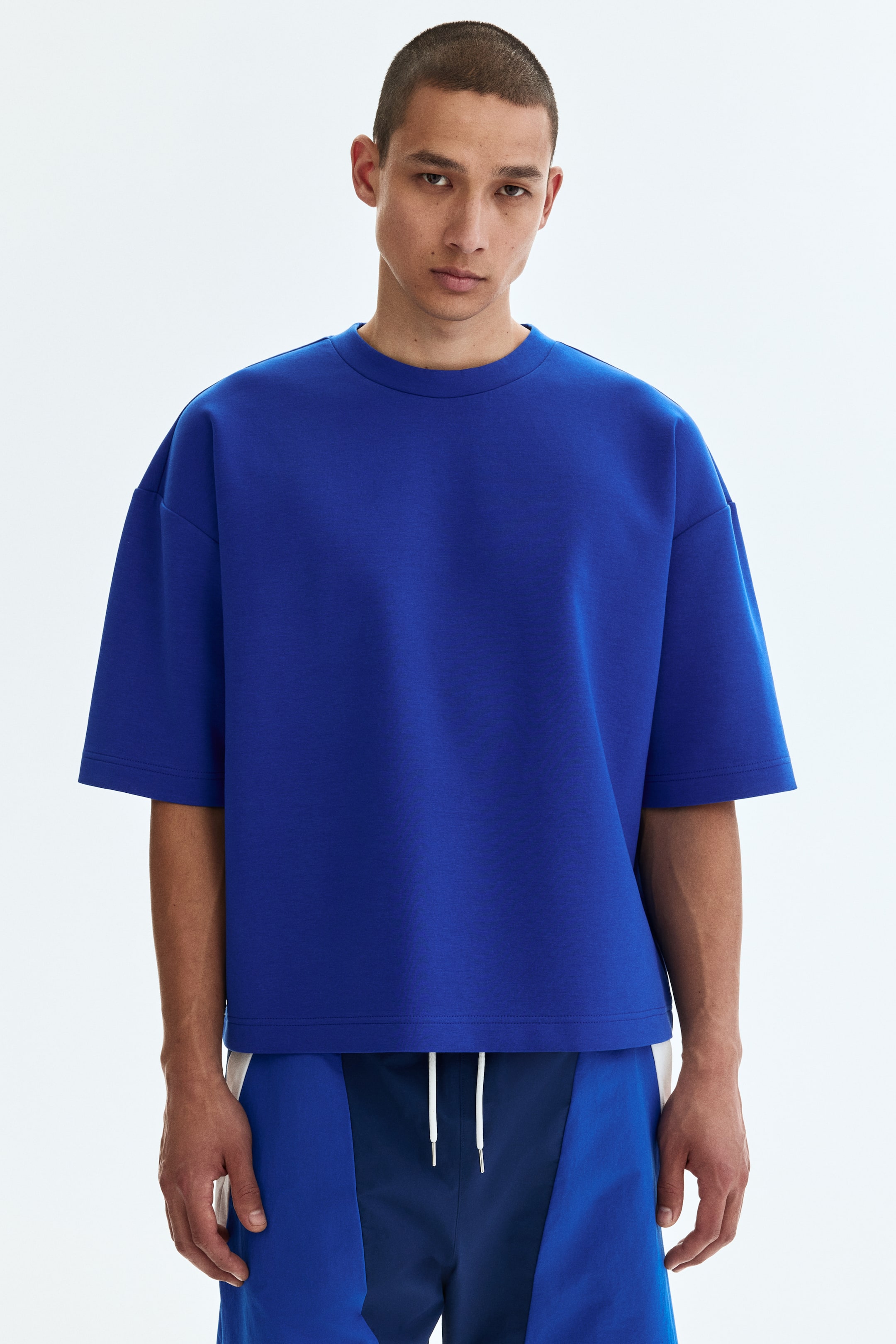 Grösseres Bild ansehen: Das royalblaue Crewneck-T-Shirt ist vorne zu sehen und zeichnet sich durch eine übergroße Passform mit tief angesetzten kurzen Ärmeln und einem geraden Saum aus.