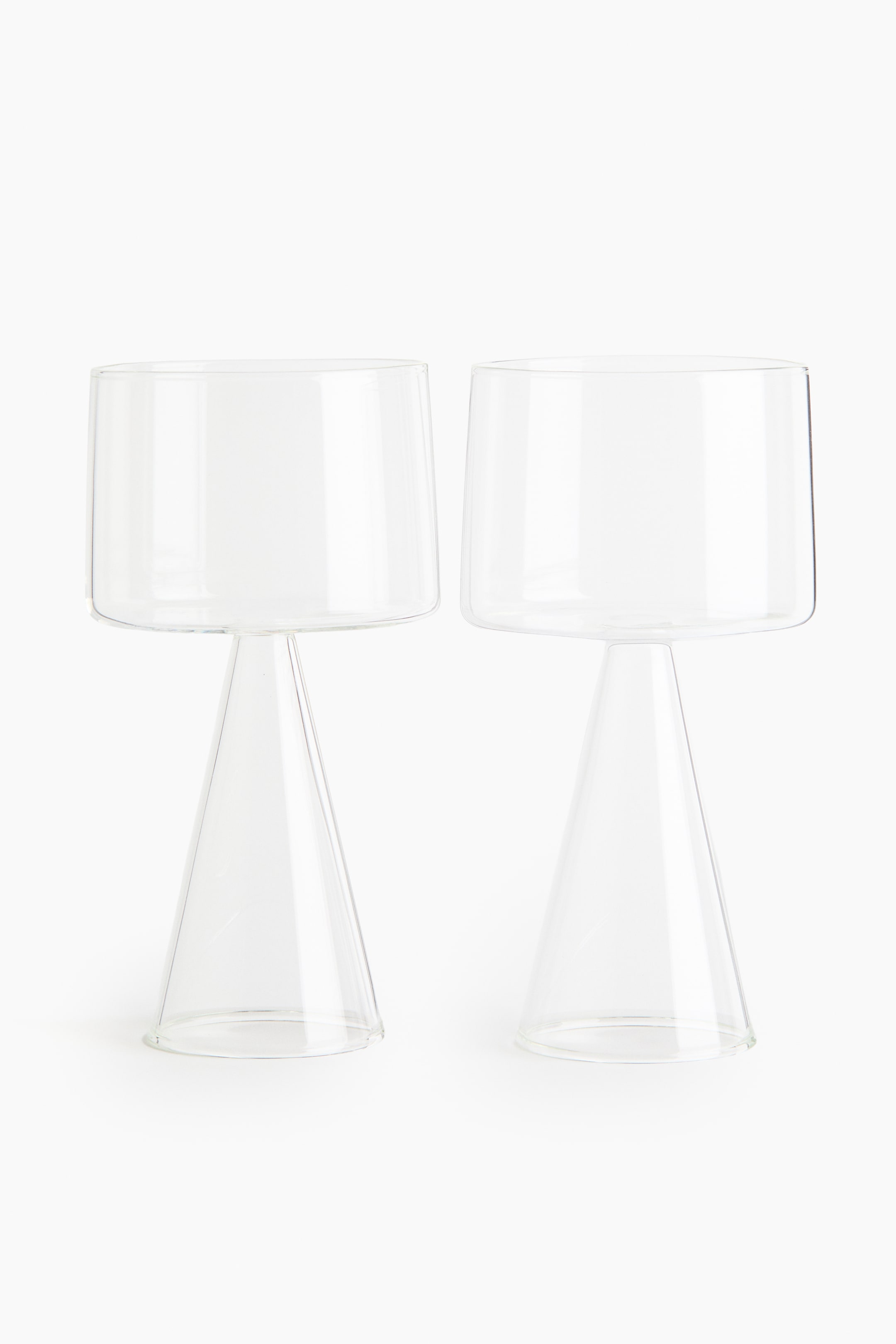 View larger image: Two wine glasses stand facing forward, each showcasing a cylindrical bowl crafted from delicate borosilicate glass, elegantly perched on a sculptural, cone-shaped base.