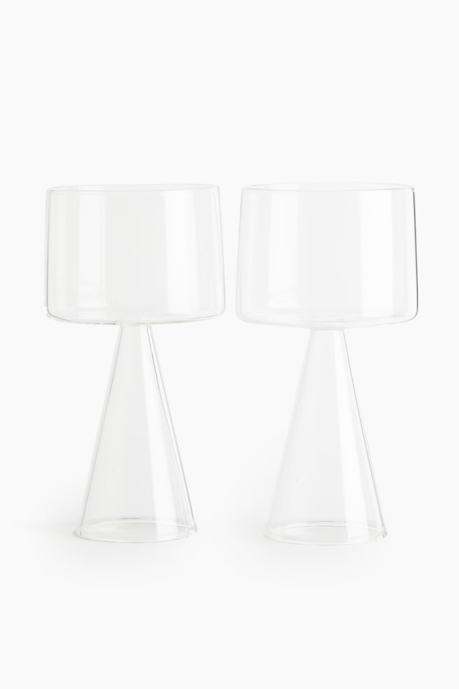 Two wine glasses are standing front-facing, each featuring a cylindrical bowl made of delicate borosilicate glass, which is resting on a sculptural, cone-shaped base. - 1