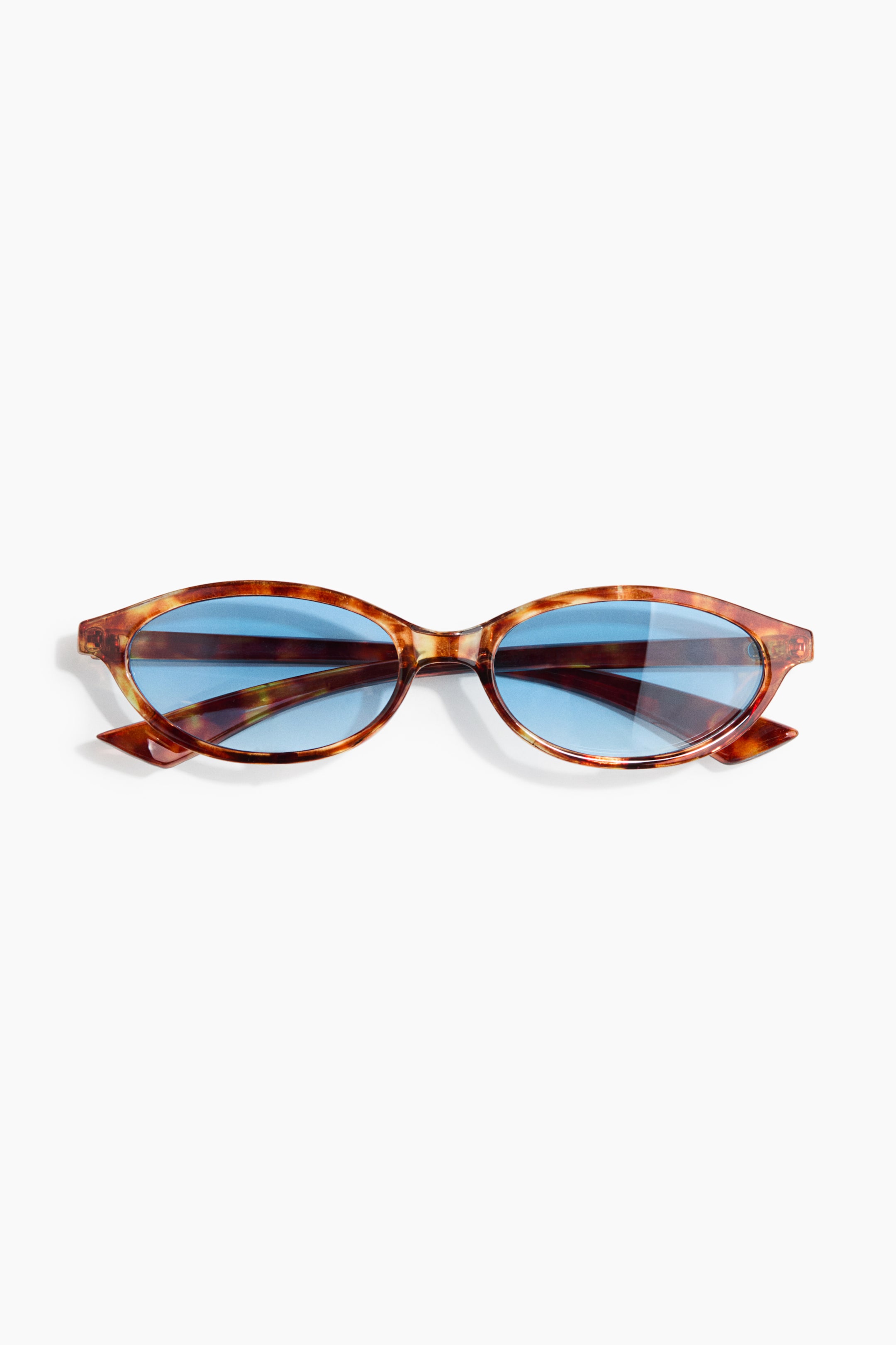 Agrandir l'image: Les lunettes de soleil ovales se présentent de face, avec des montures en plastique au motif écaille de tortue. Elles sont équipées de verres en plastique teintés bleus, offrant une protection UV.