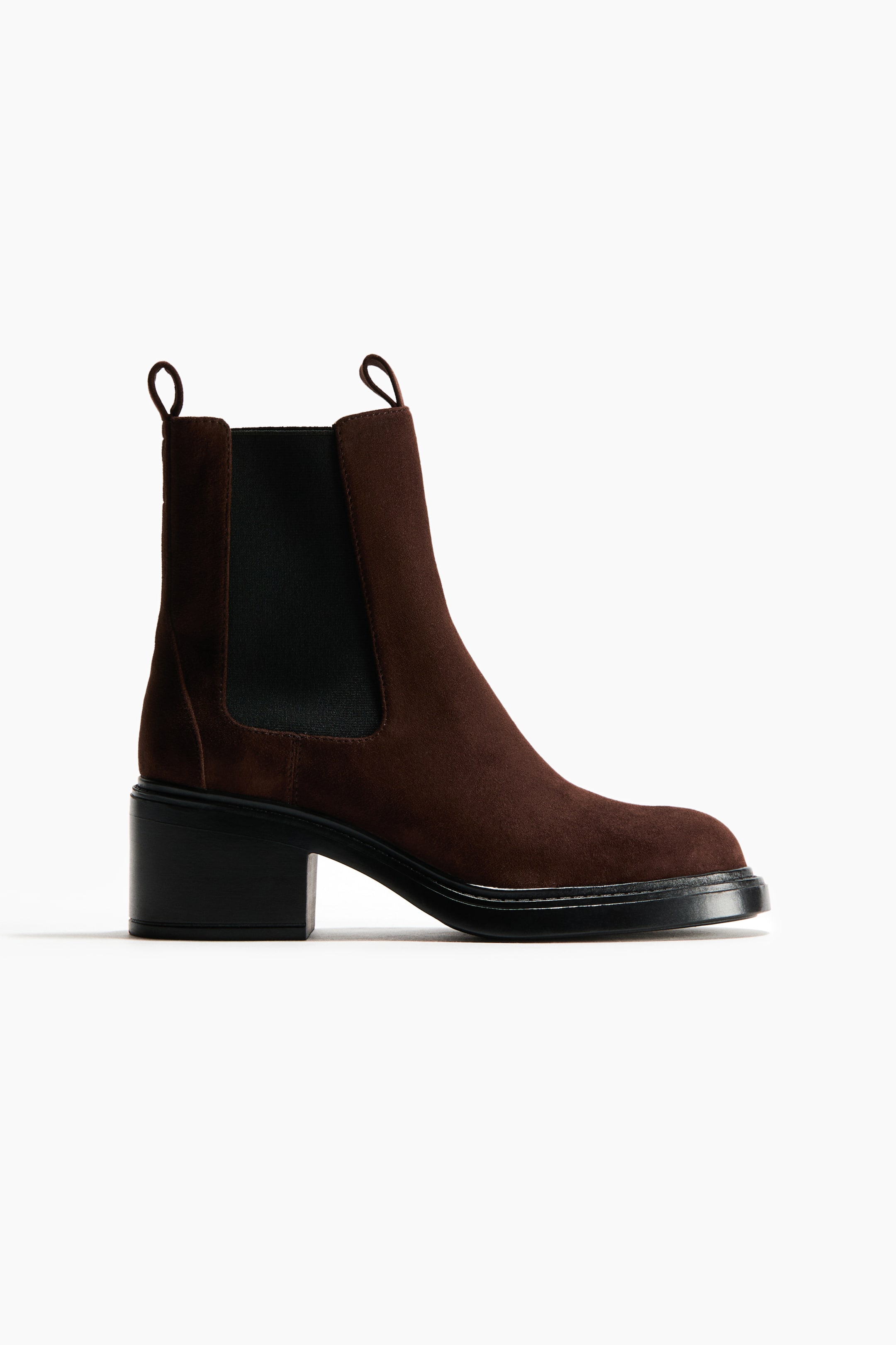 View larger image: A dark brown suede Chelsea boot is shown from the side, featuring a rounded toe and a black block heel. It also has black elastic side panels, two pull tabs at the top of the shaft, and a black chunky sole.
