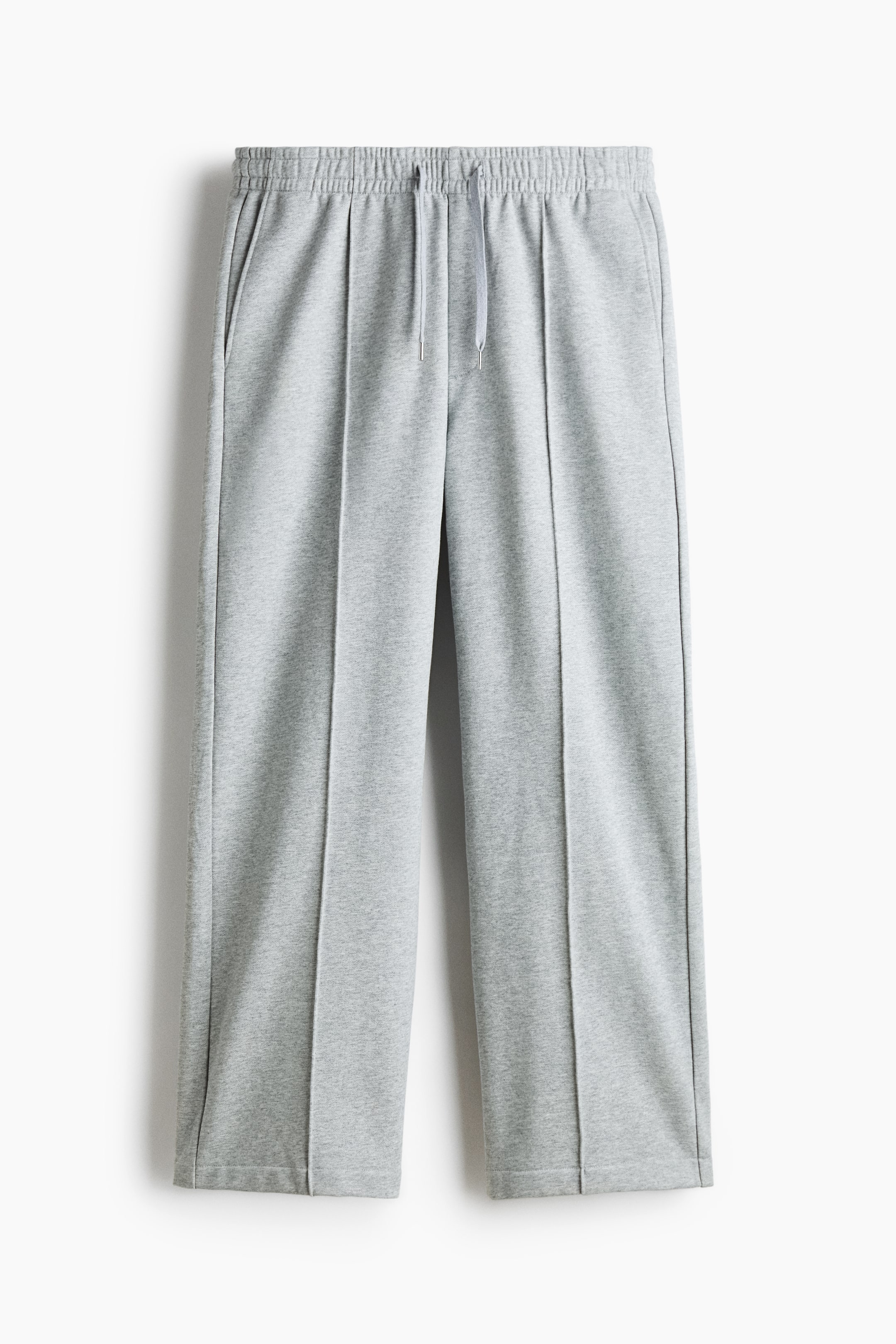 View larger image: Grey sweatpants are featuring an elasticated waistband with a visible grey drawstring and two side pockets at the front. A stitched crease is running down the centre front of each leg, which is finishing with a plain hem.