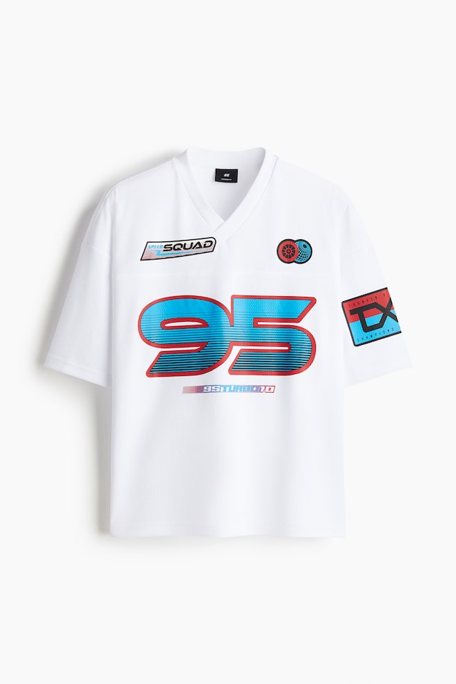 Vista frontale di un top bianco a maniche corte con scollo a V in stile jersey, realizzato in un tessuto traforato. Presenta una grande grafica "95" blu e rossa con strisce orizzontali sul petto e un testo più piccolo "95TURBO10" sotto di essa. Il top mostra anche una patch "SPEED SQUAD" sul petto sinistro, un design circolare rosso e blu sul petto destro e una patch "THUNDER Z CHAMPION" sulla manica destra. - 1