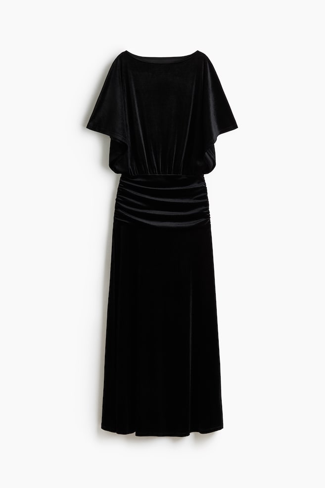 A black velvet dress is hanging facing front, showcasing a boat neckline and draped, cape-like short sleeves. The dress features a horizontally ruched waist panel that leads into a straight, flowing skirt. - 1