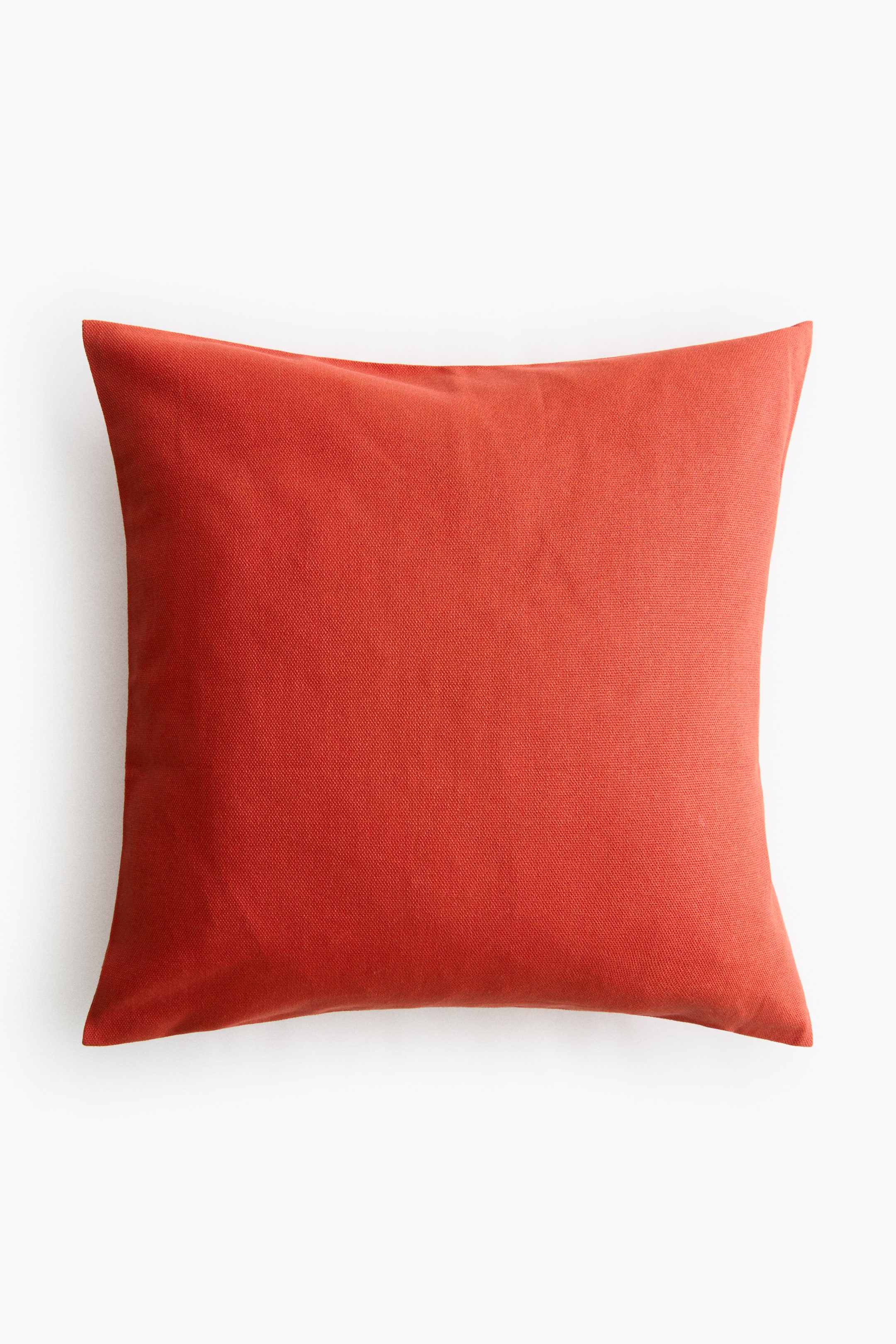 View larger image: A square cushion cover in reddish-orange cotton canvas is positioned facing forward, displaying a subtle weave texture. It appears slightly plumped and is designed with a concealed zip.
