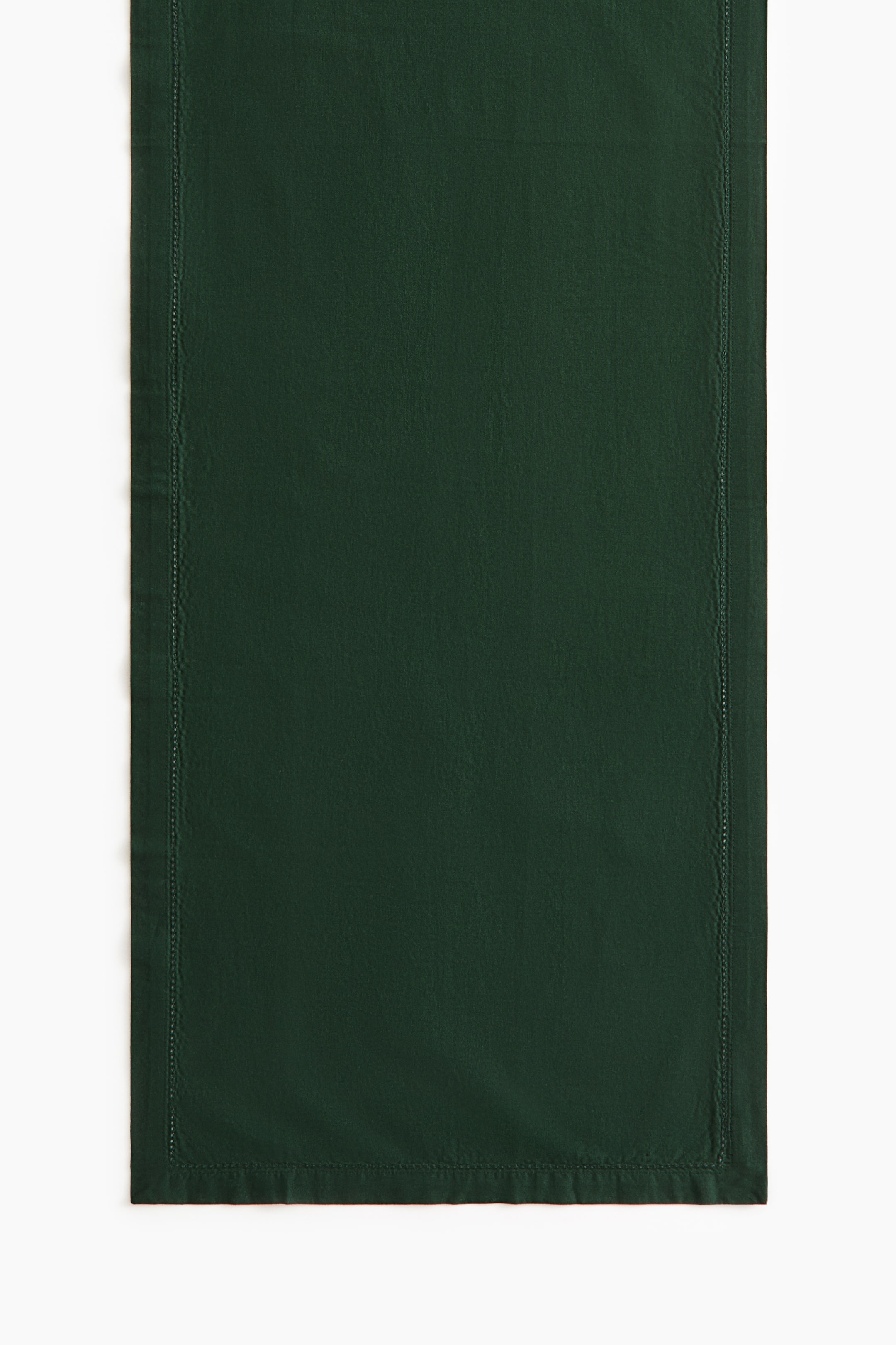 View larger image: A dark green cotton table runner is laid flat, facing front, showcasing a delicate hemstitched border running along the inner edges. The runner features a wide, folded hem along the outer borders.