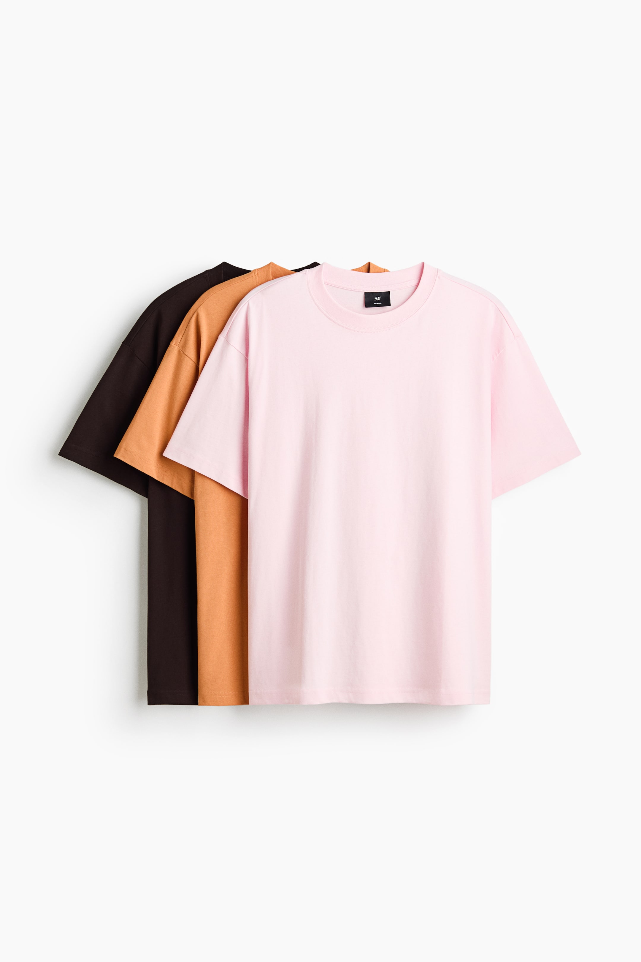View larger image: The front of three t-shirts is displayed, with a light pink t-shirt at the forefront, followed by a caramel t-shirt, and a dark brown t-shirt at the back. Each t-shirt showcases a round, rib-trimmed neckline, a straight-cut hem, and a relaxed fit.