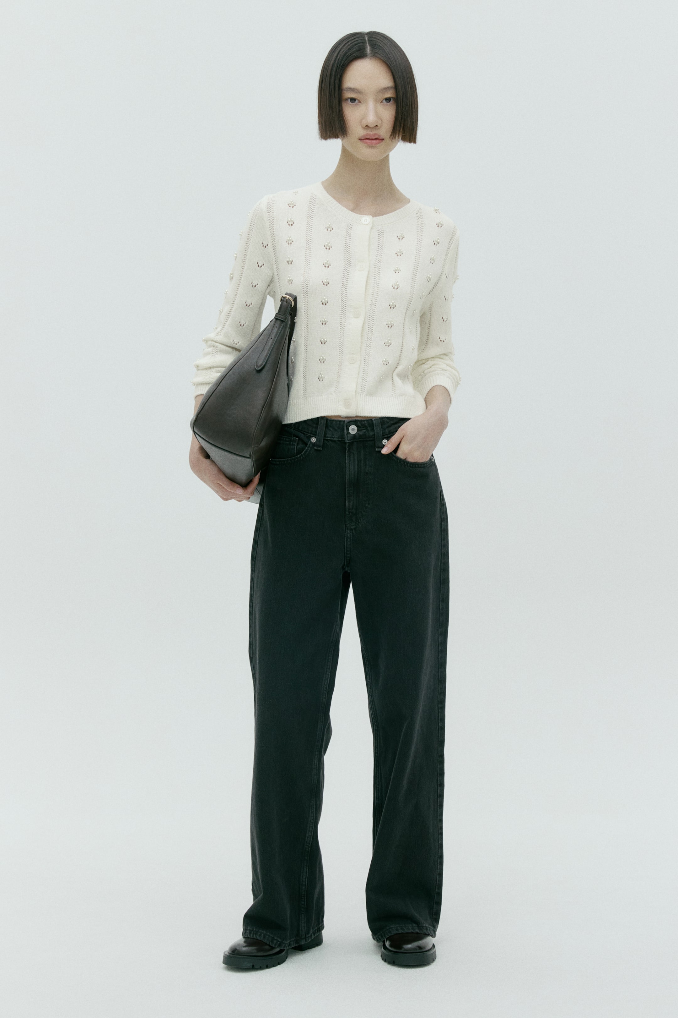 이미지 확대 보기: 크림색 버튼 여밈 카디건은 라운드 네크라인, 긴 소매, 크롭 기장의 밑단을 특징으로 하며 세로로 배열된 정교한 오픈워크 플로럴 패턴이 돋보입니다.