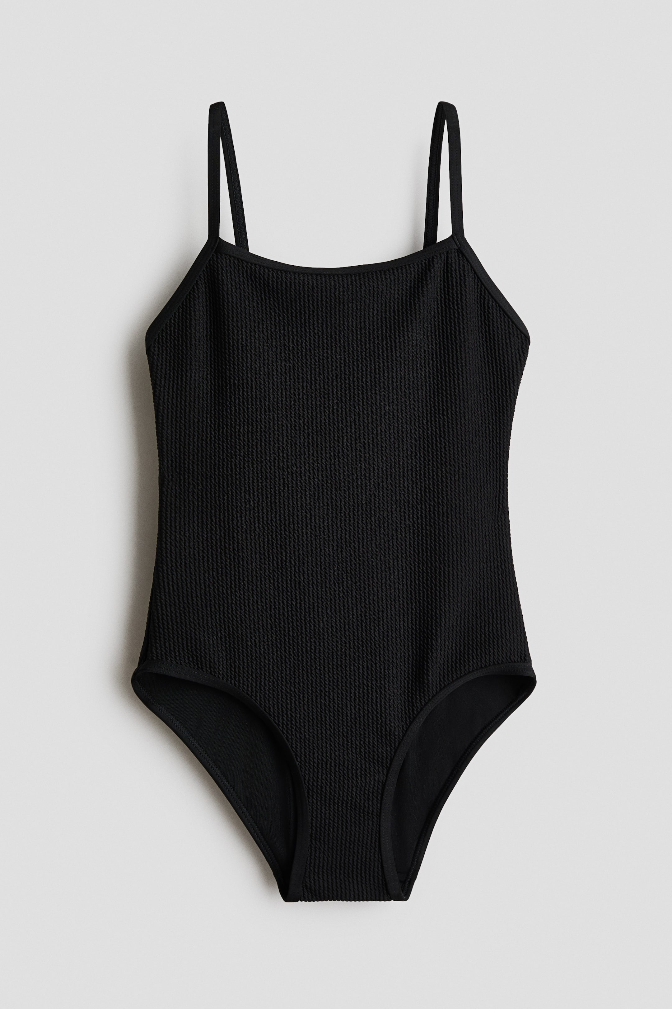 Voir une image plus grande: Le maillot de bain noir entièrement doublé présente un tissu texturé, un décolleté carré et des bretelles étroites. Il est présenté de face, montrant une doublure visible aux ouvertures des jambes et à l'encolure.
