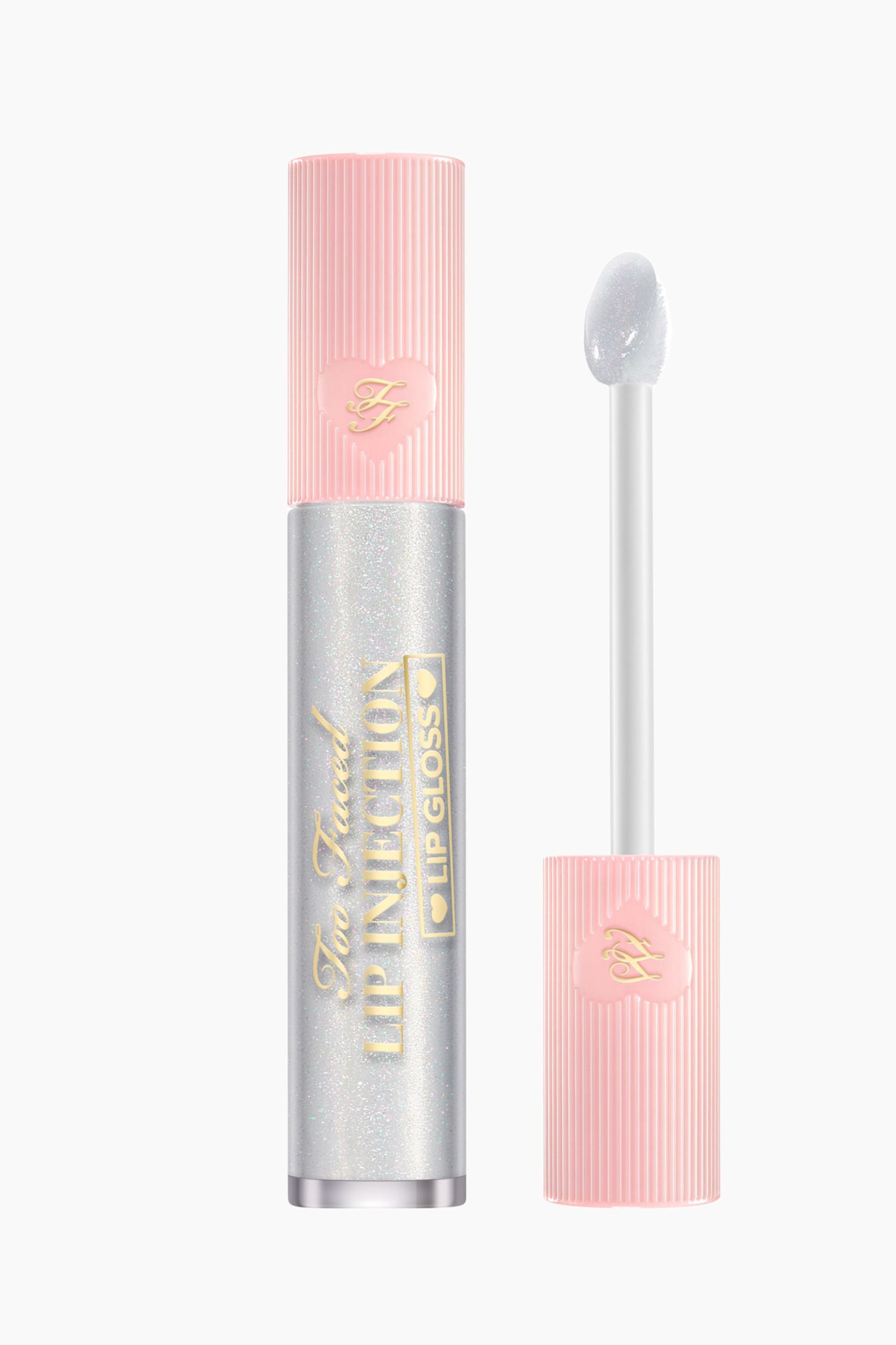 Visa större bild: En cylindrisk läppglansförpackning står upprätt och ser silverfärgad och glittrande ut med guldtexten "Too Faced LIP INJECTION LIP GLOSS". Dess rosa ribbade lock, som har en guldig "FF"-logotyp i ett hjärta, är placerat bredvid den, med en vit applikatorstav som sträcker sig från locket och ett klart, skimrande läppglans som täcker dess hjärtformade spets.