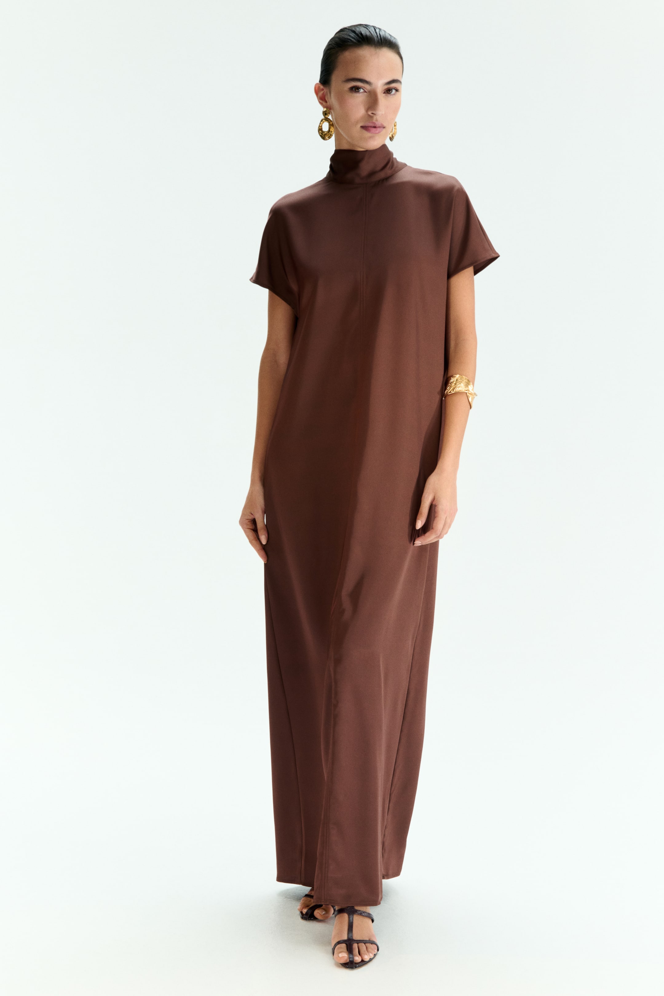 View larger image: The brown maxi dress is featuring a high neck and short sleeves, presenting a loose, flowing silhouette. A vertical seam is running down the center front of the dress.