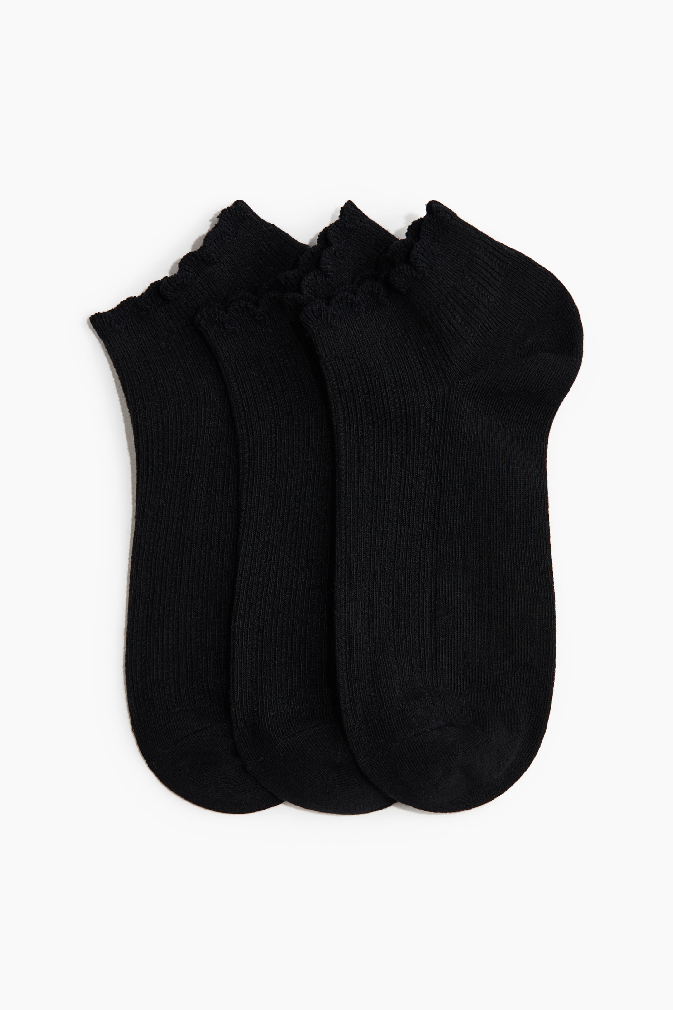 Agrandir l'image: Trois chaussettes noires à la cheville présentent leurs côtés avant, chacune arborant une bordure à volants et un corps en maille côtelée. Les chaussettes sont disposées verticalement et se chevauchent légèrement, révélant des sections lisses au niveau des orteils et des talons.