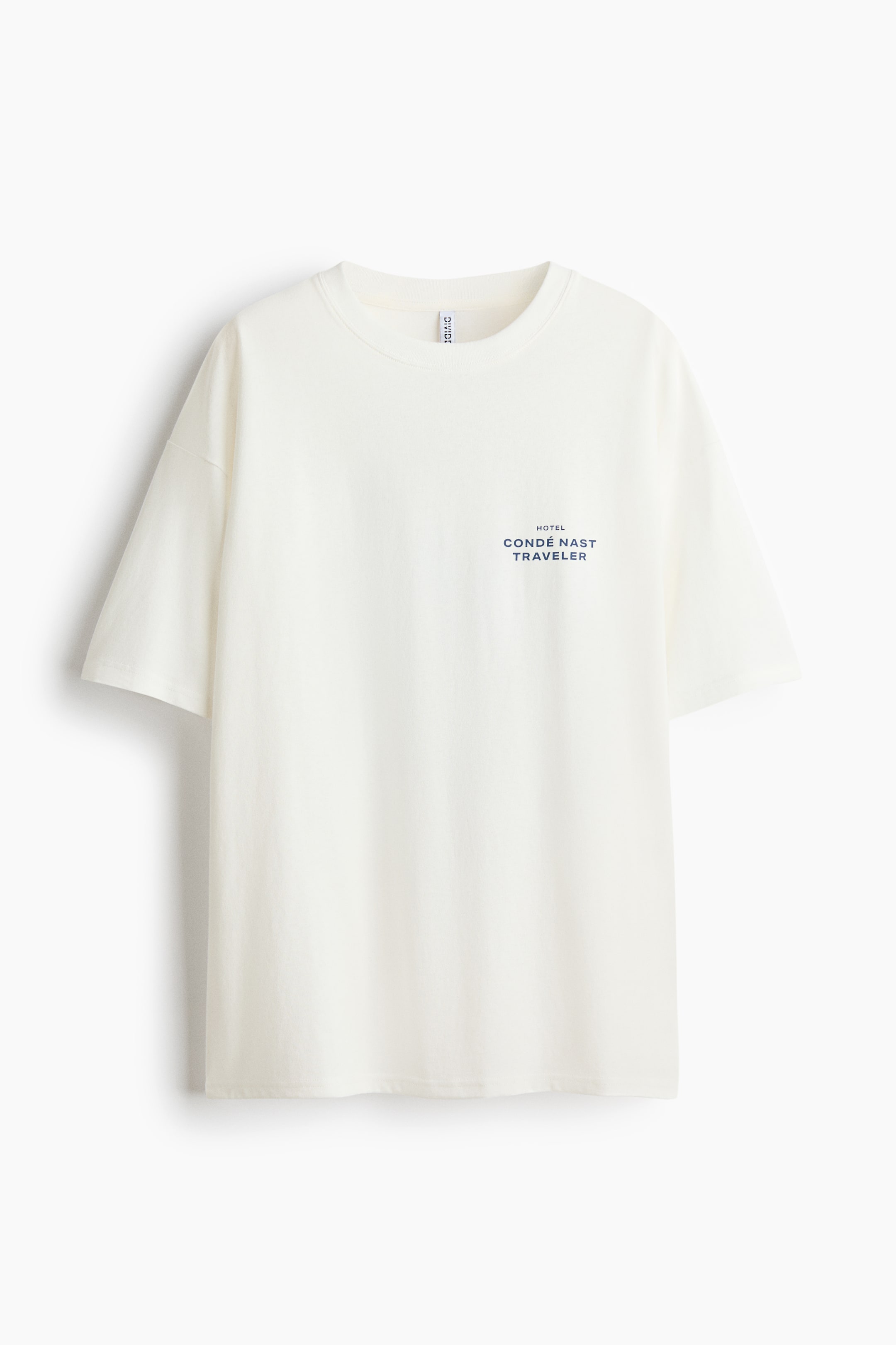 Voir une image plus grande: Un t-shirt crème surdimensionné en jersey de coton doux imprimé présente sa vue de face. Il est doté d'une bordure côtelée autour de l'encolure, d'épaules tombantes, et d'un texte bleu foncé "HOTEL CONDÉ NAST TRAVELER" centré sur la partie supérieure de la poitrine.