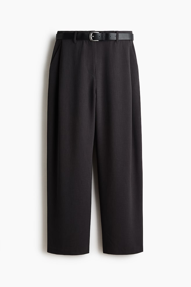 A pair of black wide-leg trousers is shown front-on, featuring a high waist accented by a black belt with a silver-tone buckle. The trousers are styled with soft front pleats and side pockets, falling into a relaxed, wide-leg silhouette. - 1