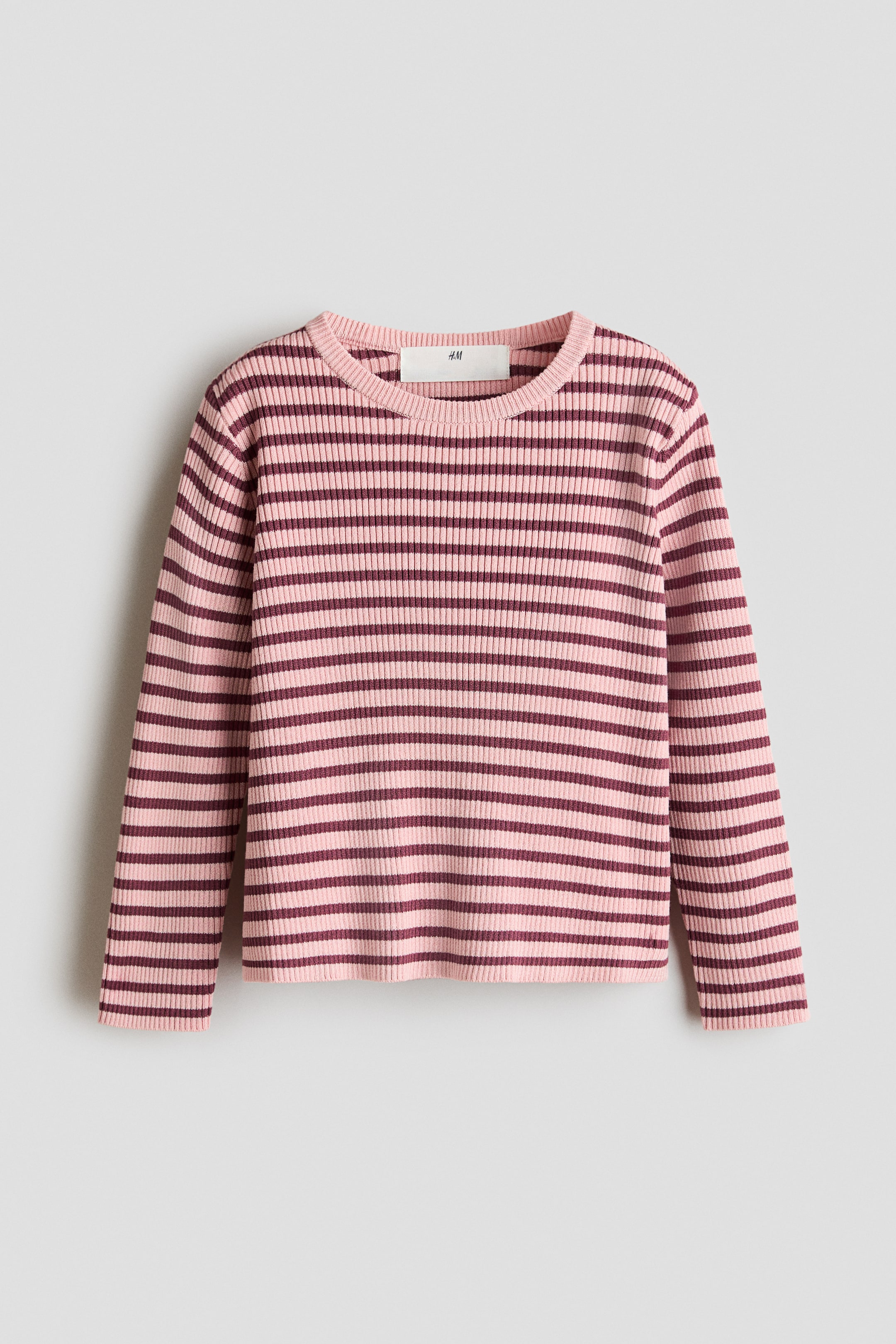View larger image: A long-sleeved ribbed knit top is shown from the front, featuring horizontal stripes in pale pink and dark maroon. It displays a ribbed crew neck, ribbed cuffs, and a ribbed hem, with a white brand label visible at the back of the neck.