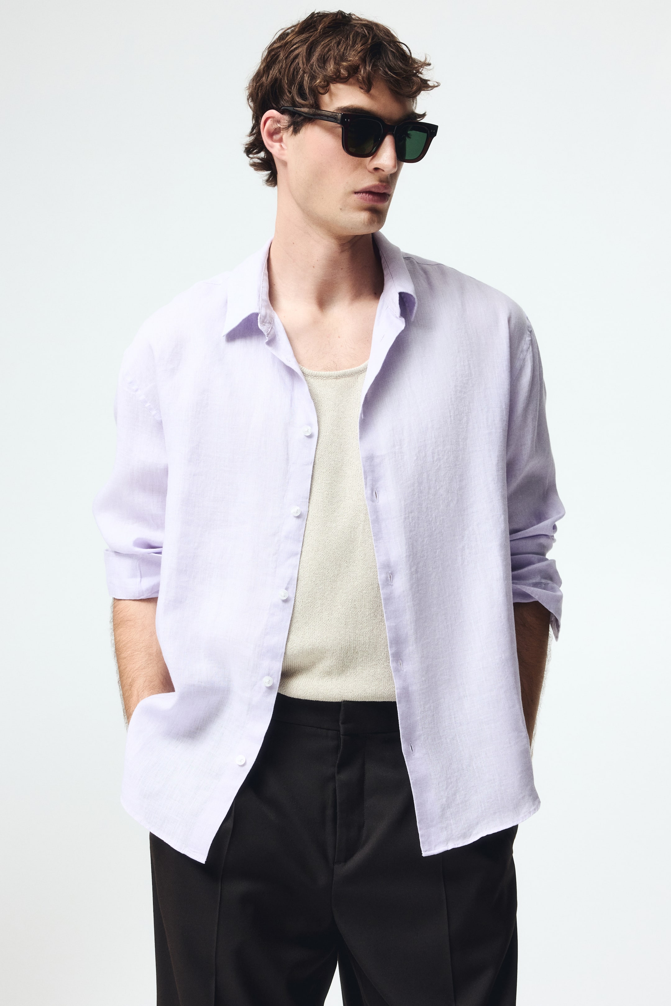 View larger image: The shirt, in a delicate shade of lavender, is crafted from a linen-blend fabric and is styled open to showcase a light-hued ribbed tank top beneath. The spread collar elegantly frames the neckline, while the long sleeves are casually rolled up at the cuffs. The front placket is neatly lined with white buttons, adding a touch of sophistication.