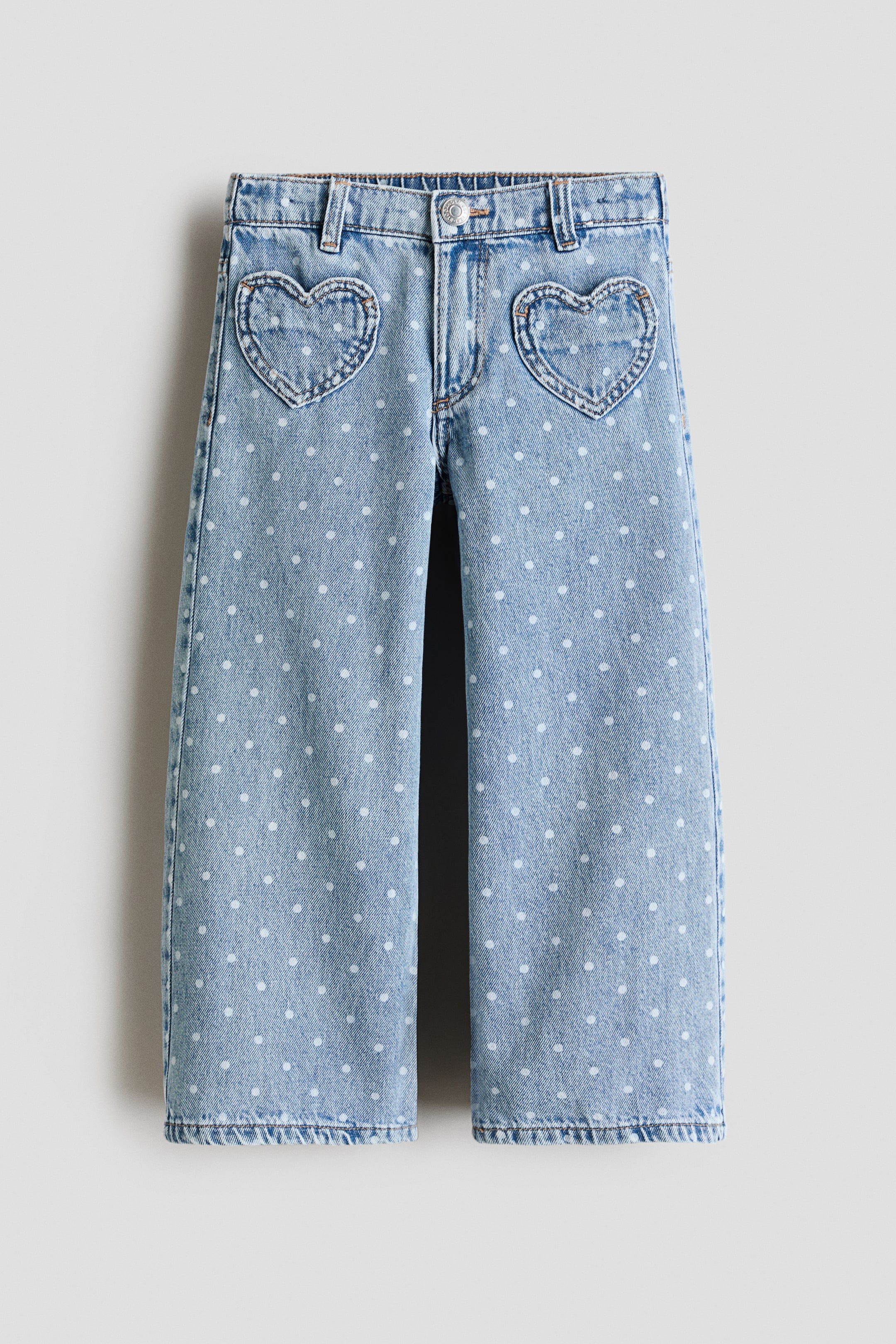 View larger image: Light wash denim jeans showcasing a wide-leg cut with a white polka dot pattern throughout. They feature two heart-shaped front pockets, a standard waistband, and belt loops.