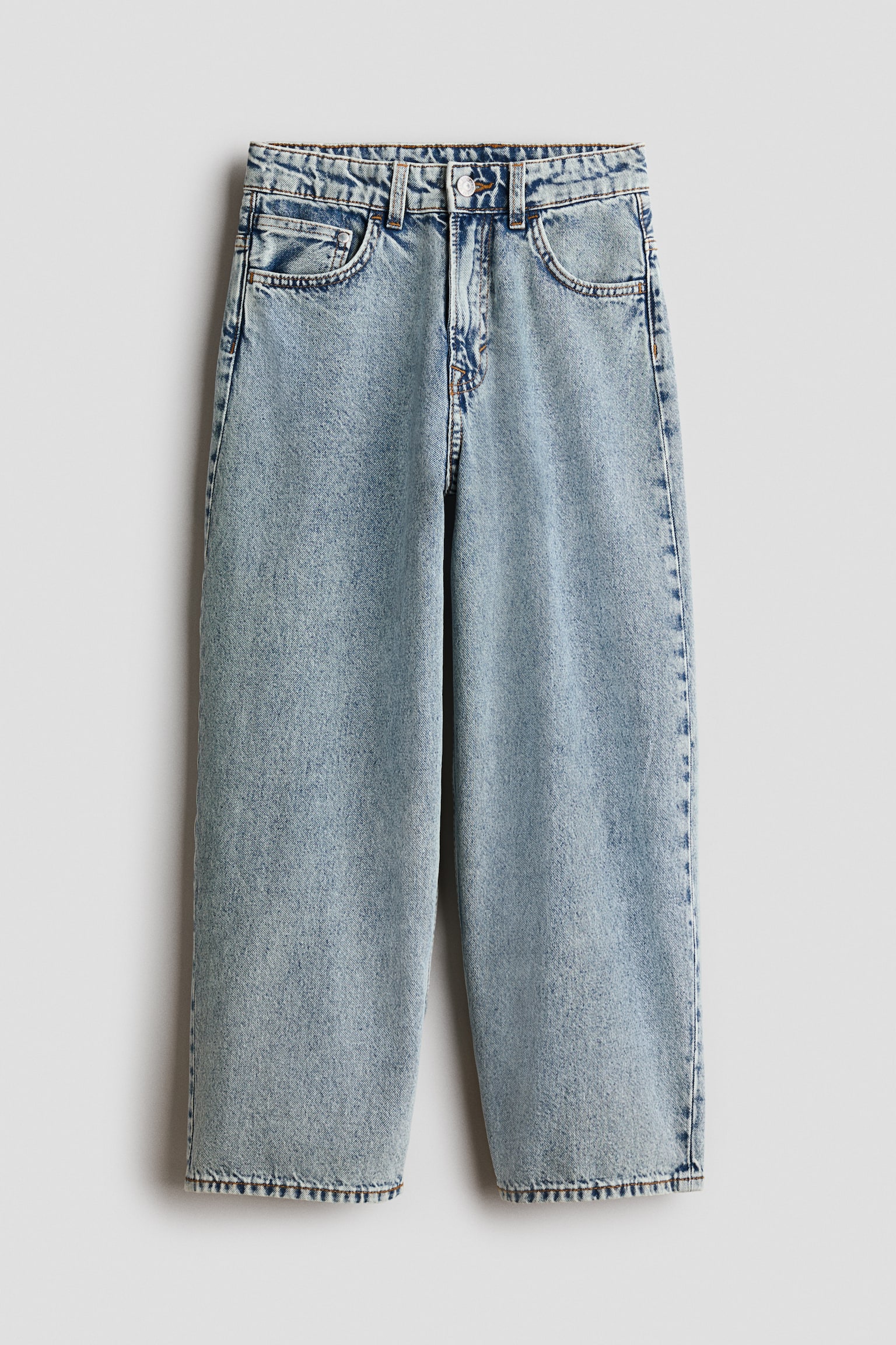 Light blue washed cotton denim jeans are hanging in a front-facing view, showcasing a baggy, wide-leg fit and a classic five-pocket design. The jeans feature a regular waist with belt loops, a button closure, and a zip fly.