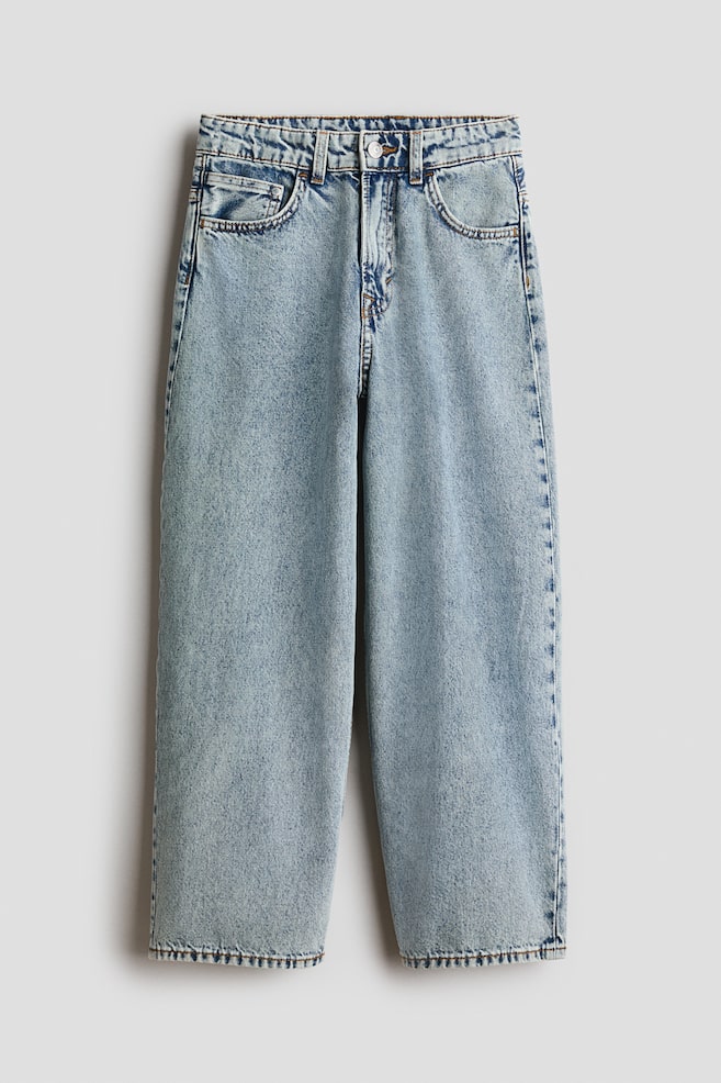 Jeans de mezclilla de algodÃ³n lavada en azul claro colgados en vista frontal, mostrando un ajuste holgado de pierna ancha y el clÃ¡sico diseÃ±o de cinco bolsillos. Los jeans presentan tiro regular con trabillas para cinturÃ³n, cierre de botÃ³n y bragueta con cierre. - 1