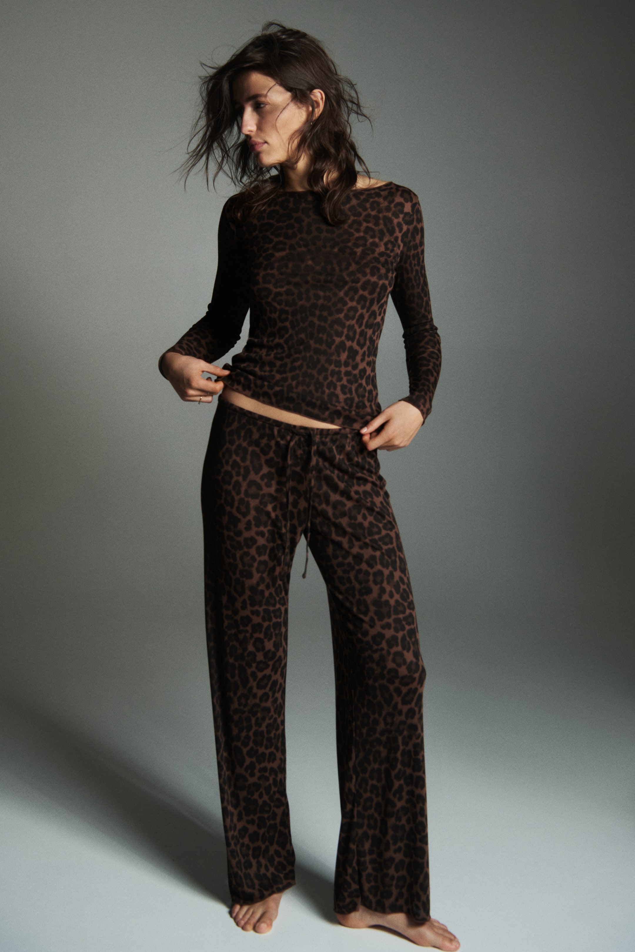 View larger image: A brown leopard-print loungewear set features a long-sleeved top with a boat-neck and wide-leg pants with a drawstring waist. The top fits close to the body, and the pants drape loosely, highlighting the comfortable design.