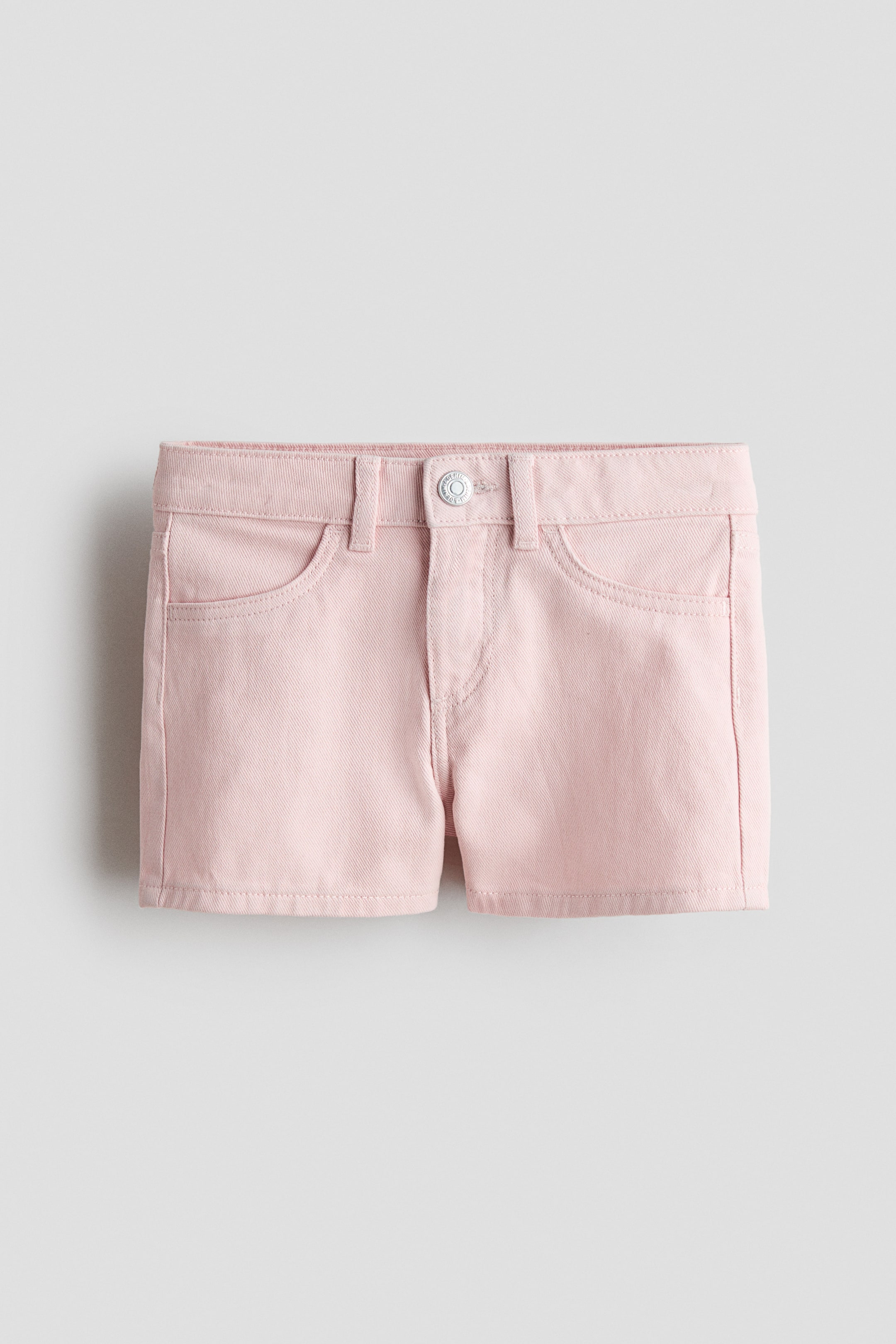Agrandir l'image: Short en denim de coton rose, vue de face, avec une ceinture à passants, un bouton argenté, une fermeture éclair et deux poches avant incurvées.