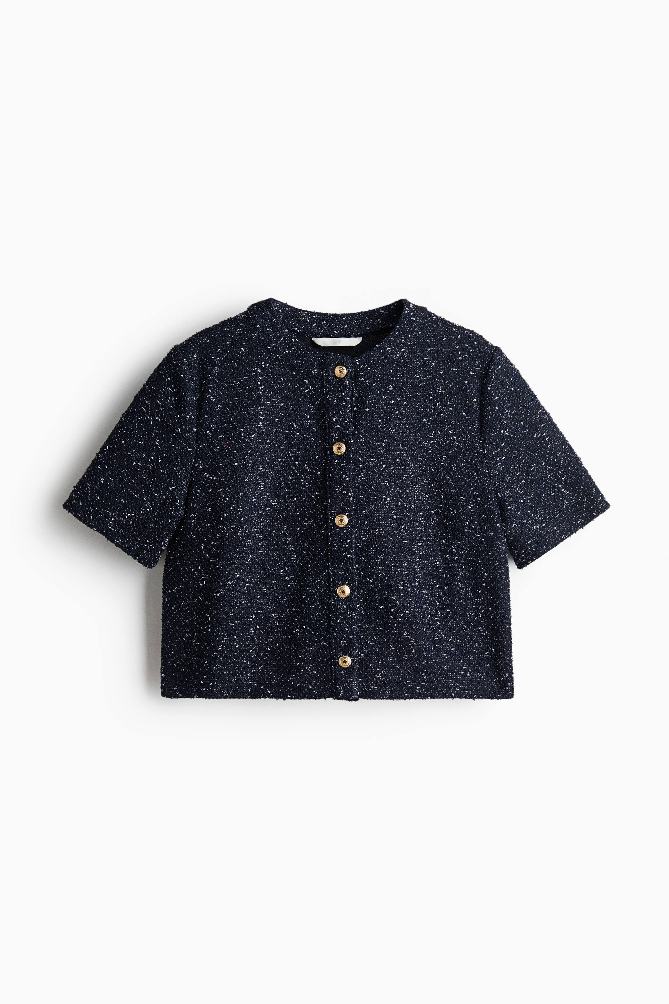 View larger image: A dark blue short-sleeved jacket is shown from the front, featuring textured tweed fabric with white speckles. It is designed with a band collar and a full button-front closure, accented by five gold-toned buttons.