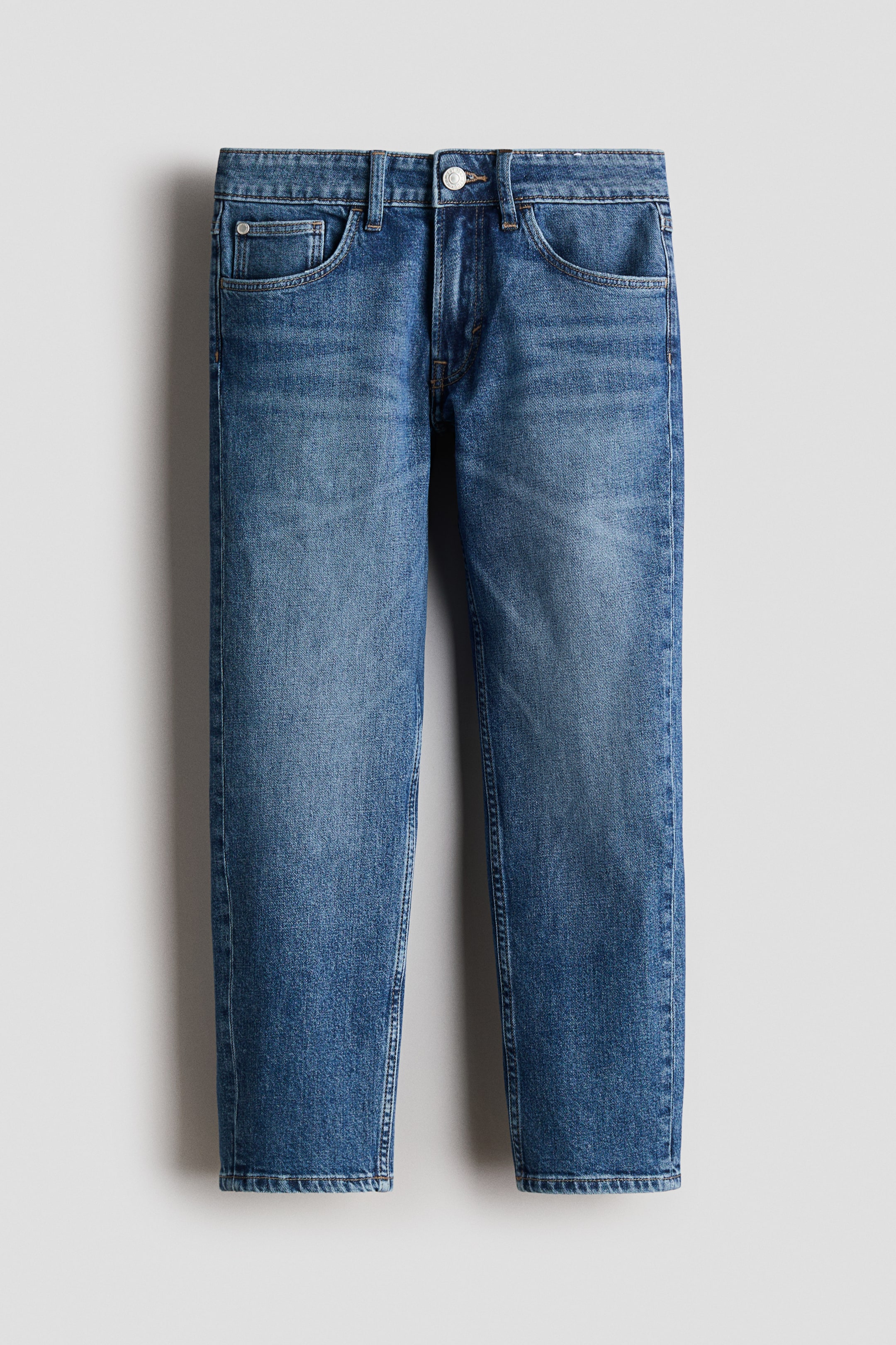 Größeres Bild ansehen: Die blau gewaschenen Denim-Jeans präsentieren eine Vorderansicht und verfügen über ein 5-Taschen-Design, einen Knopfverschluss an der Taille mit Gürtelschlaufen und eine entspannte Passform mit konisch zulaufenden Beinen.