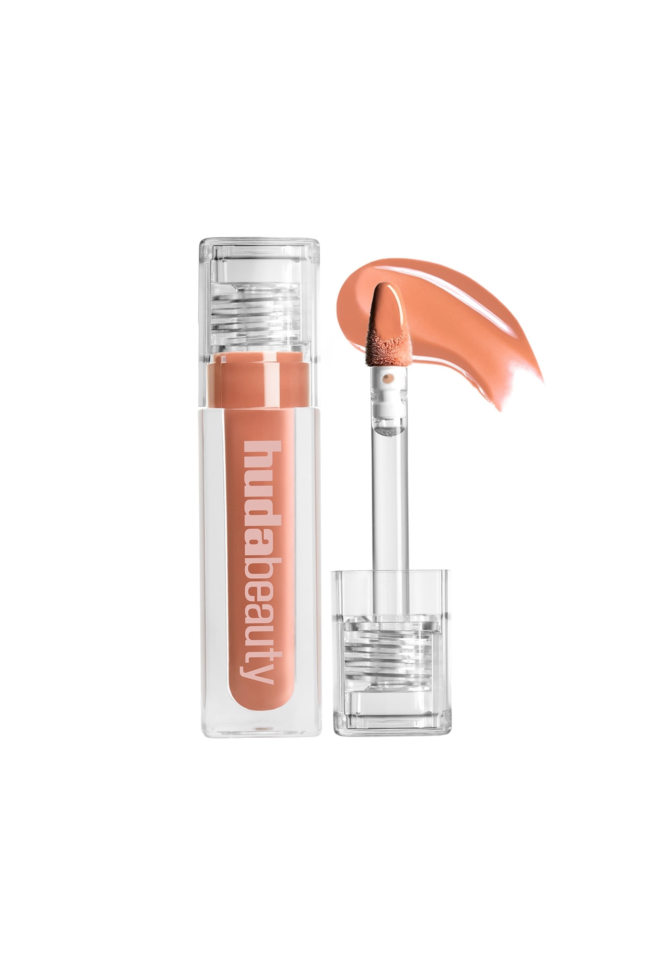 Vis større bilde: En ferskenaktig-nude lipgloss presenteres i et klart, rektangulært rør med "hudabeauty"-merkevare, vendt fremover. Dens applikator med hjorte-fot er holdt utenfor røret, dekket med glossen, med en buet prøve av produktet synlig ved siden av.